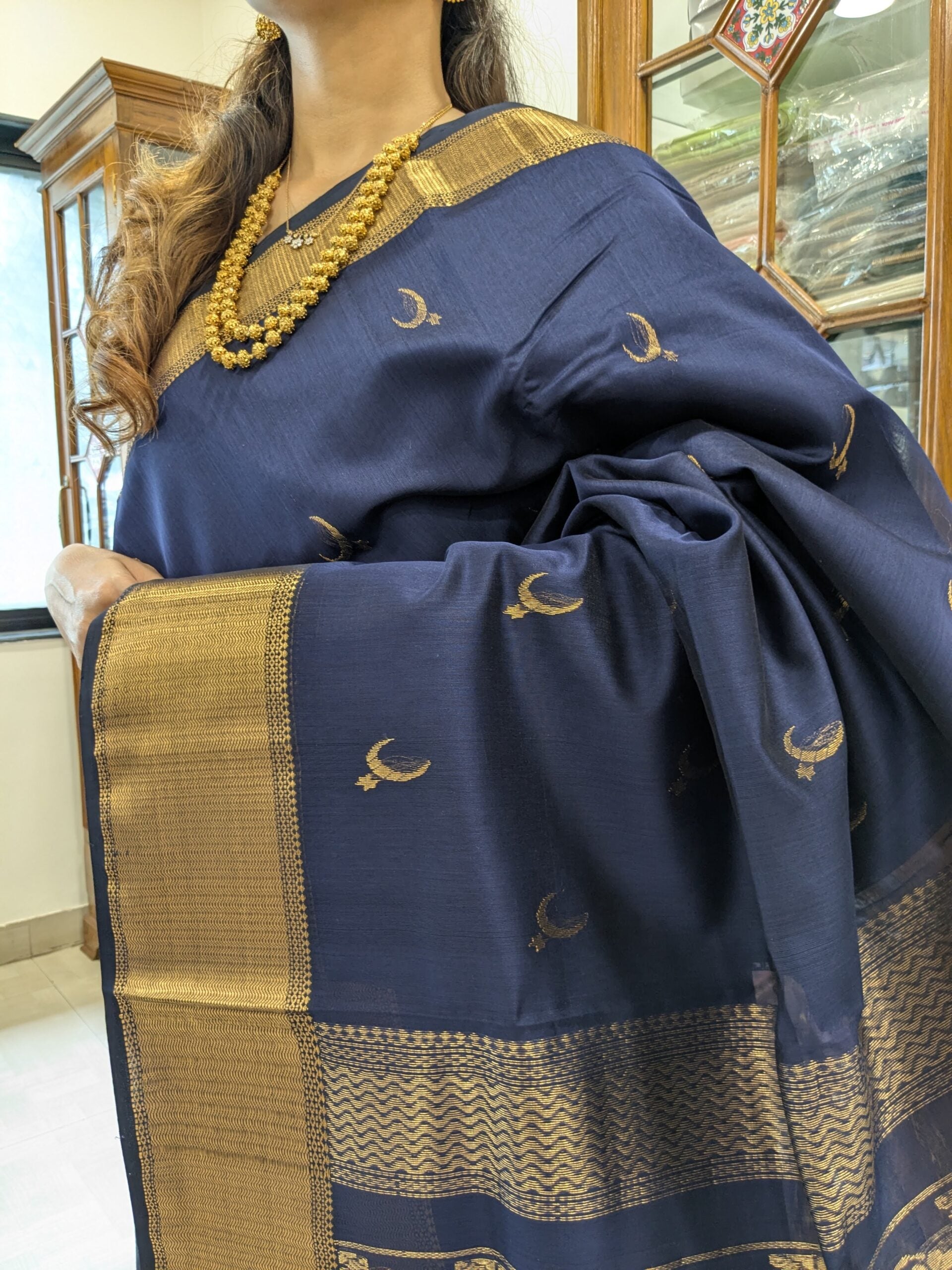 Close-up of deep blue Maheshwari saree featuring moon and flower motifs, wide-narrow border