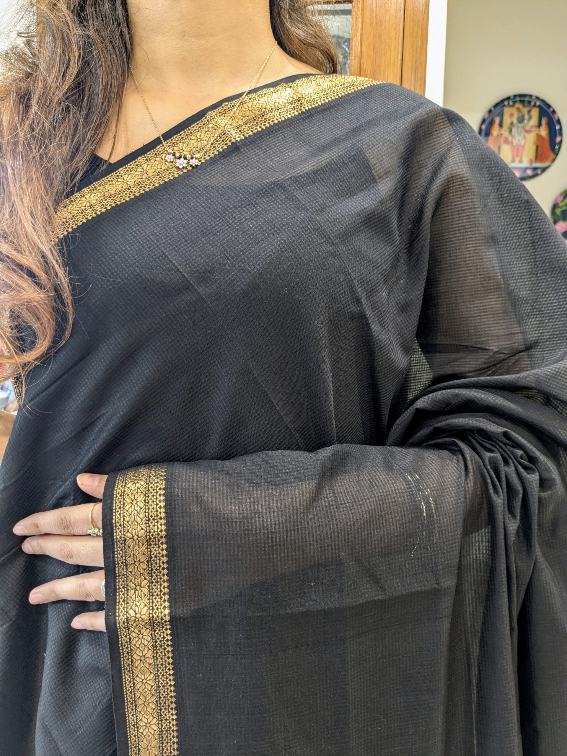 Close-up of black Maheshwari handloom saree with small checks, zari border.
