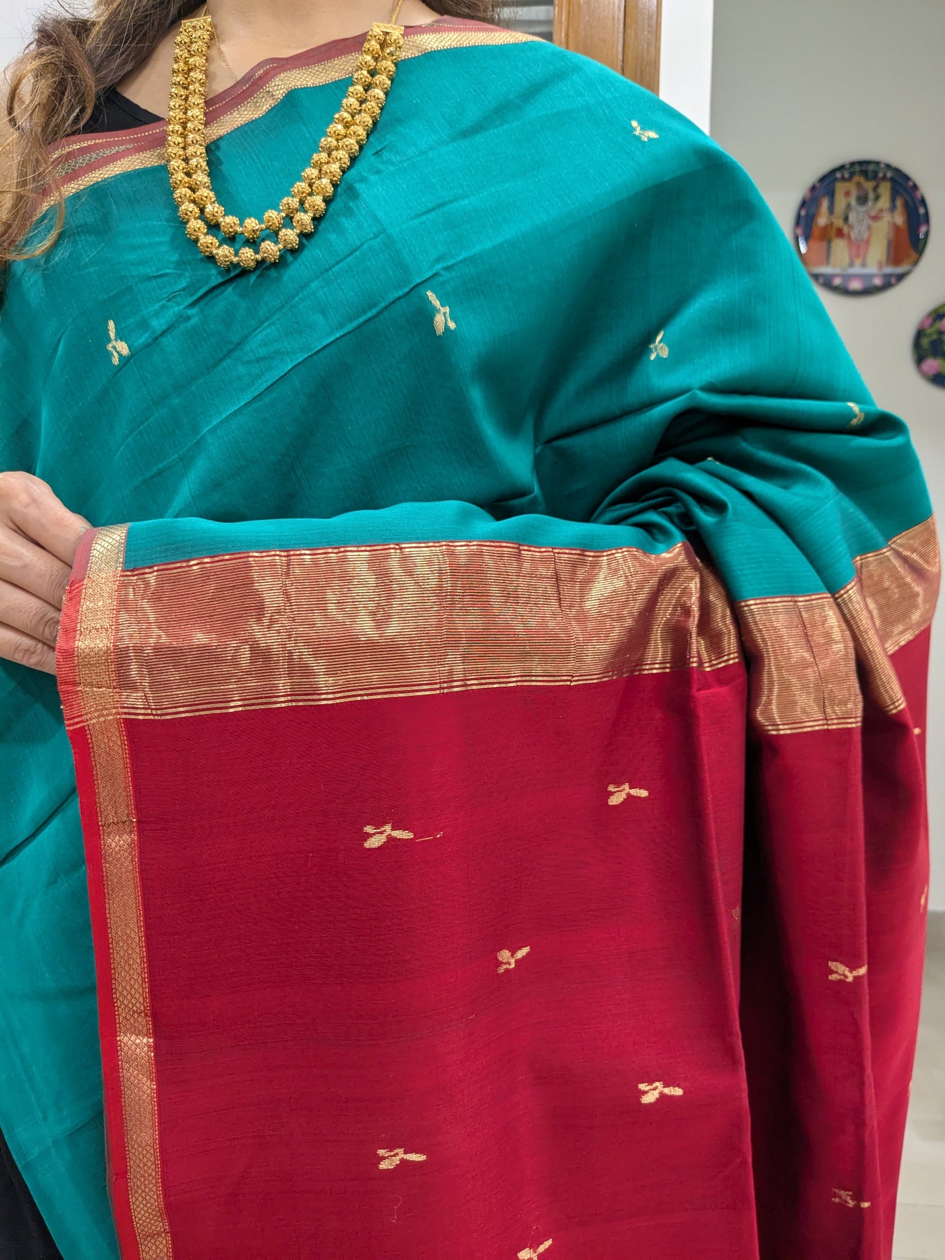 Close-up of sea green Maheshwari saree with leaf butti motifs, small border, and silk-cotton pallu transition.