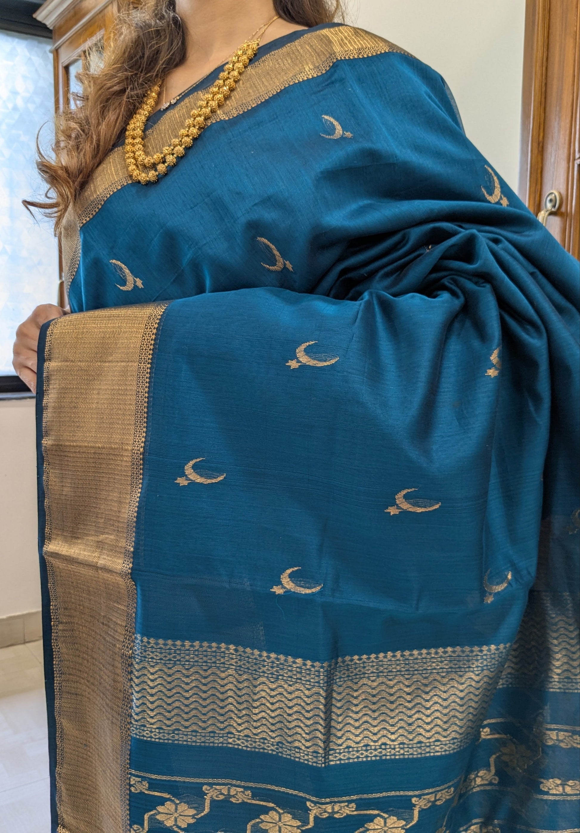 Close-up of ocean blue Maheshwari saree with moon and flower motifs, handloom weave, and detailed pallu transition.