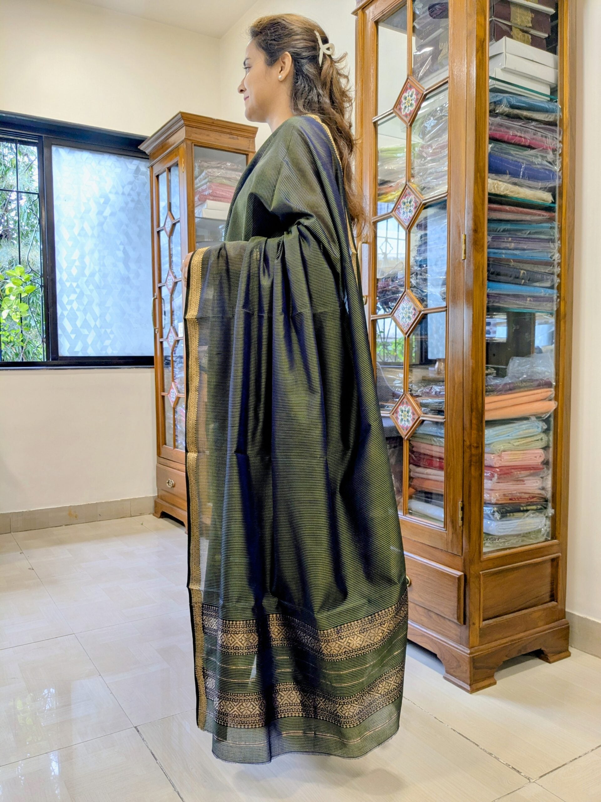 Side view of lightweight olive green saree showcasing elegant drape and handwoven texture.  