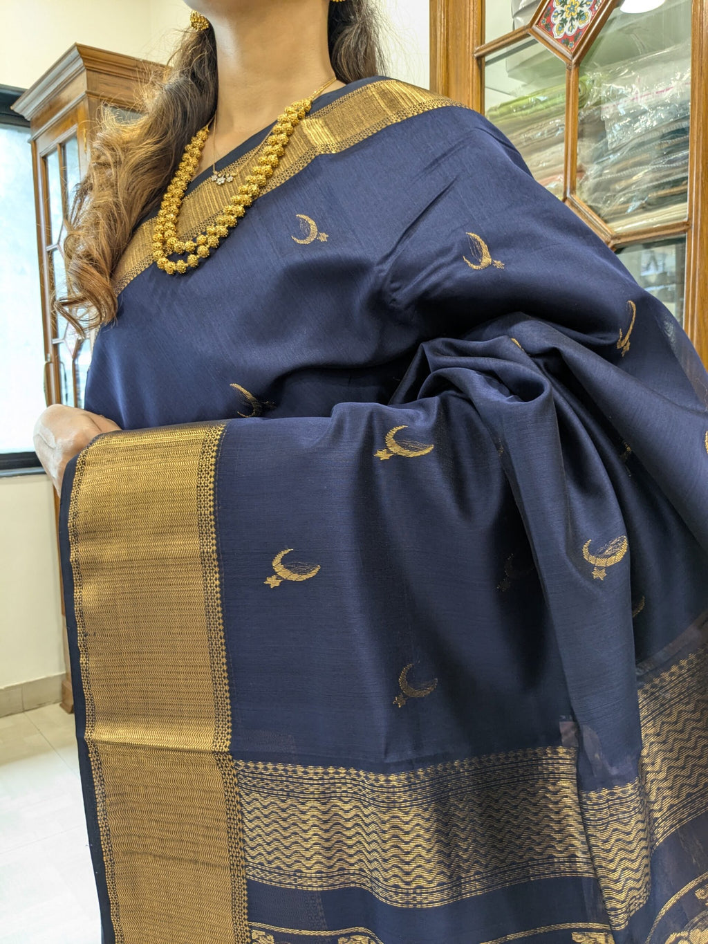 Close-up of deep blue Maheshwari saree featuring moon and flower motifs, wide-narrow border