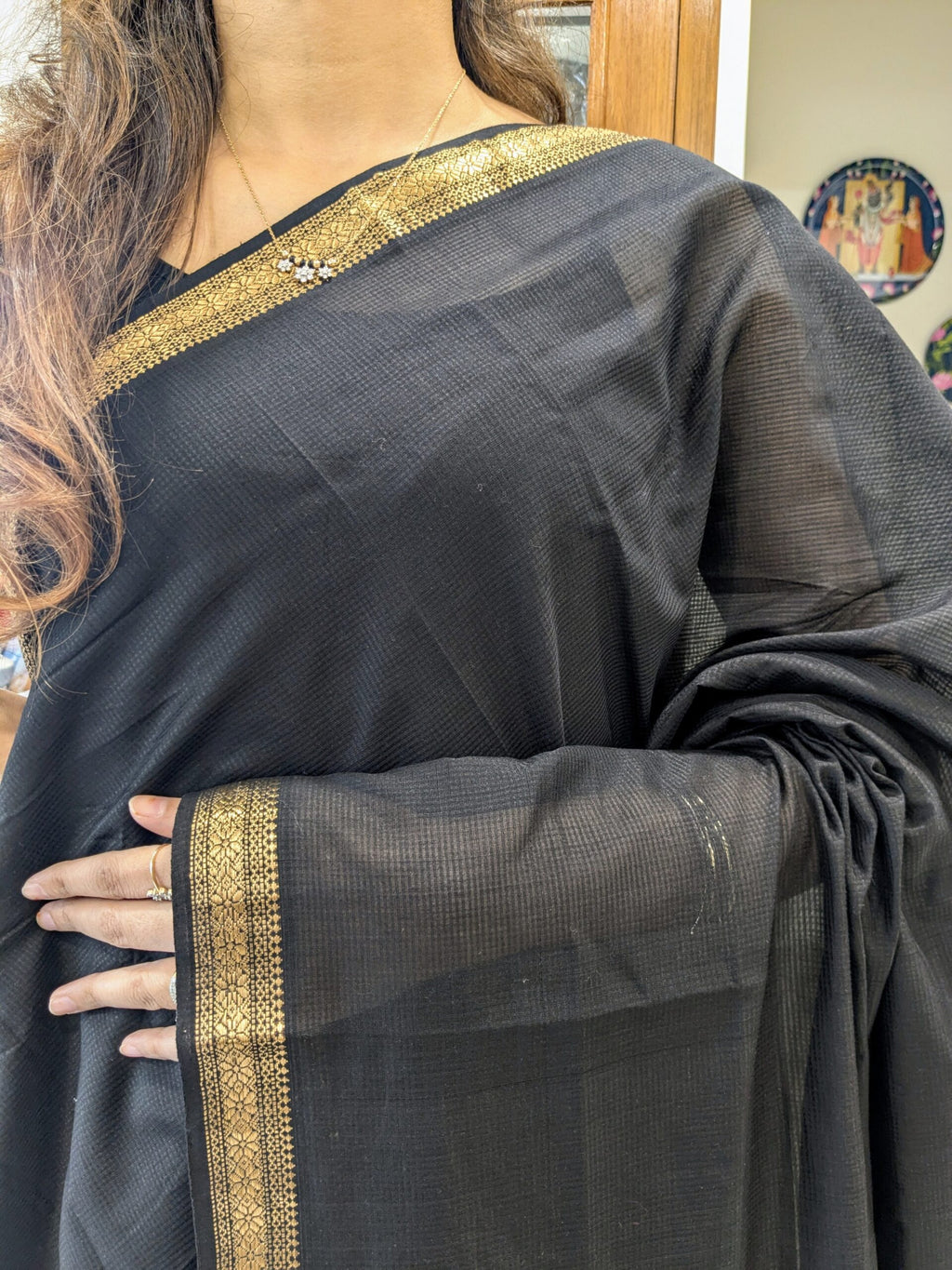 Close-up of black Maheshwari handloom saree with small checks, zari border.