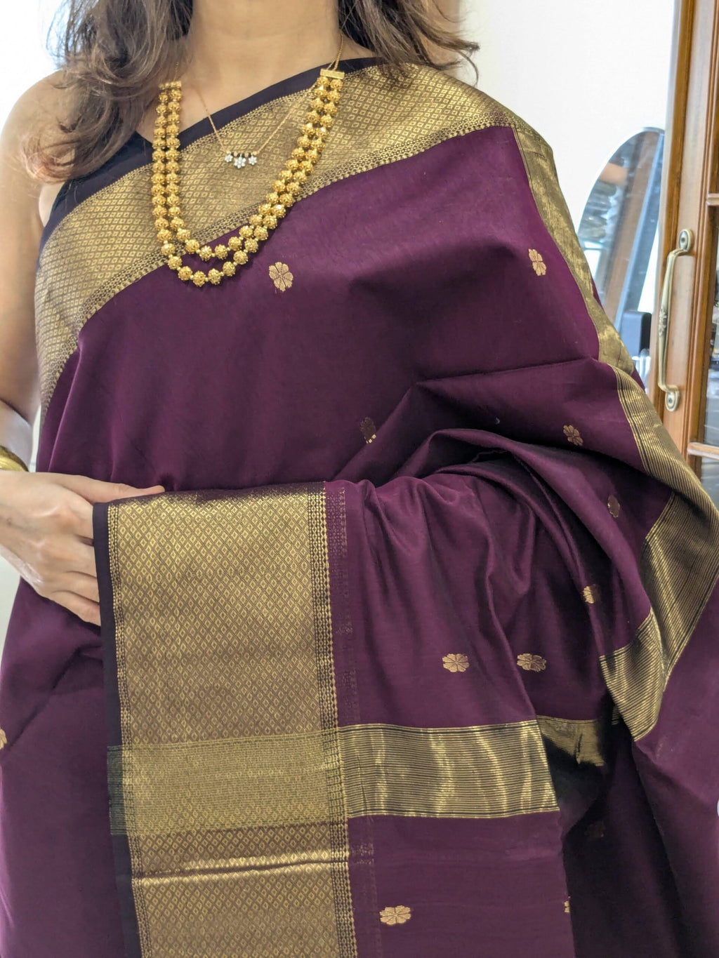 Close-up of plum purple Maheshwari silk cotton saree with flower butti, resham border