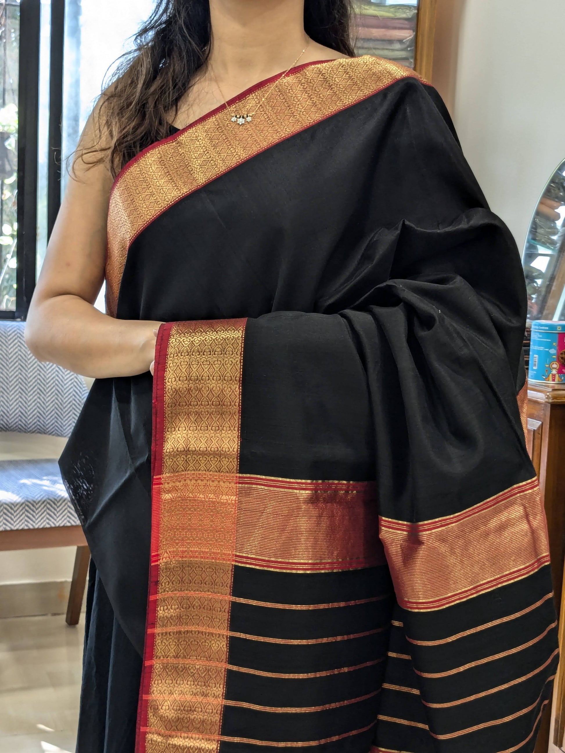 A black saree with red border indoors.