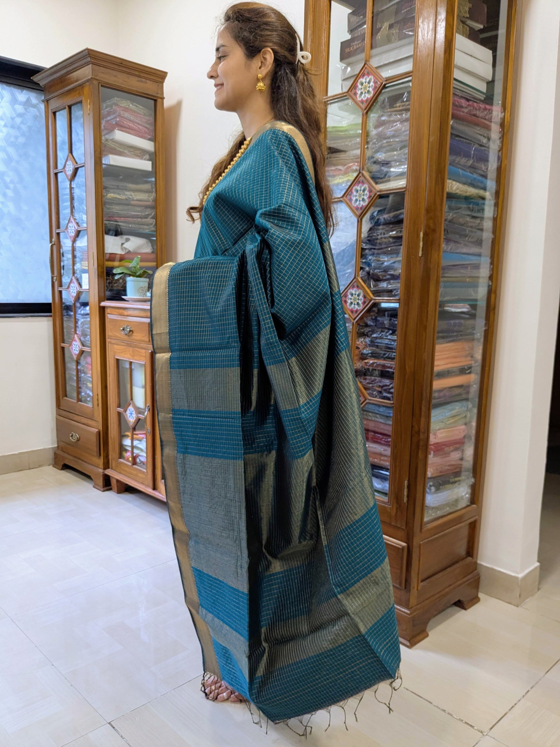 Side view of peacock blue saree showing rich drape, soft texture, and traditional zari craftsmanship.