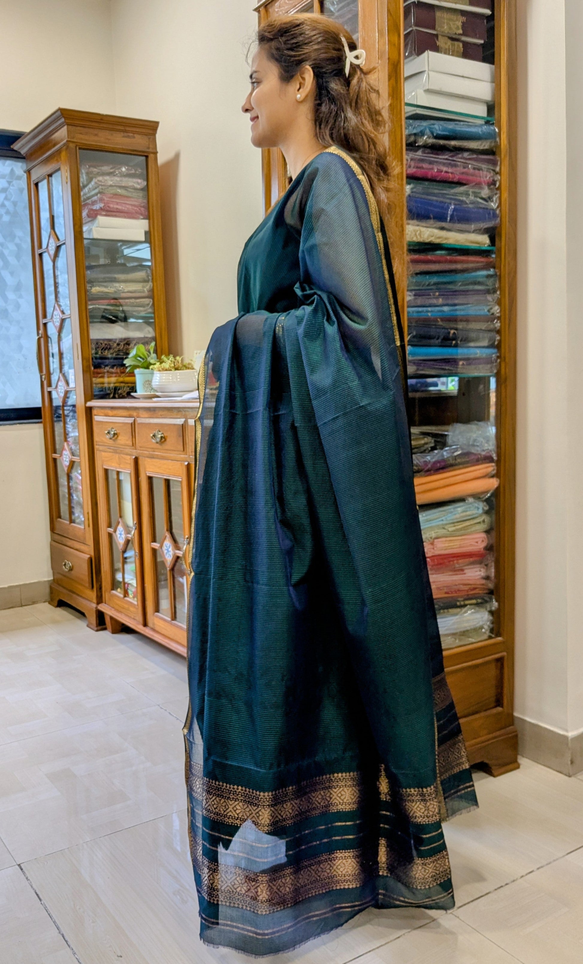Side view of bottle green saree showcasing fluid drape, subtle sheen, and fine handwoven texture.