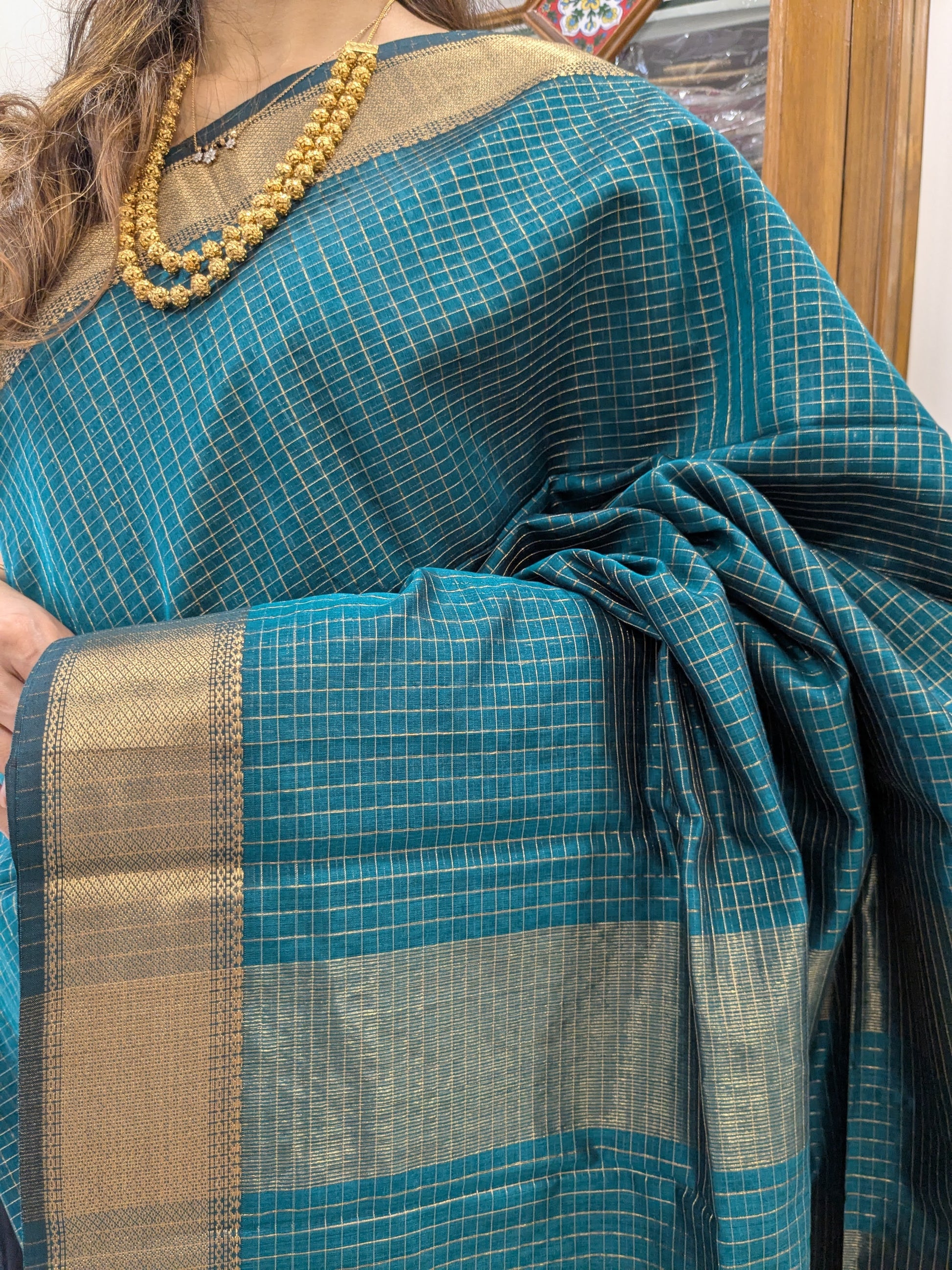 Close-up of peacock blue Maheshwari silk-cotton saree with zari checks, medium border