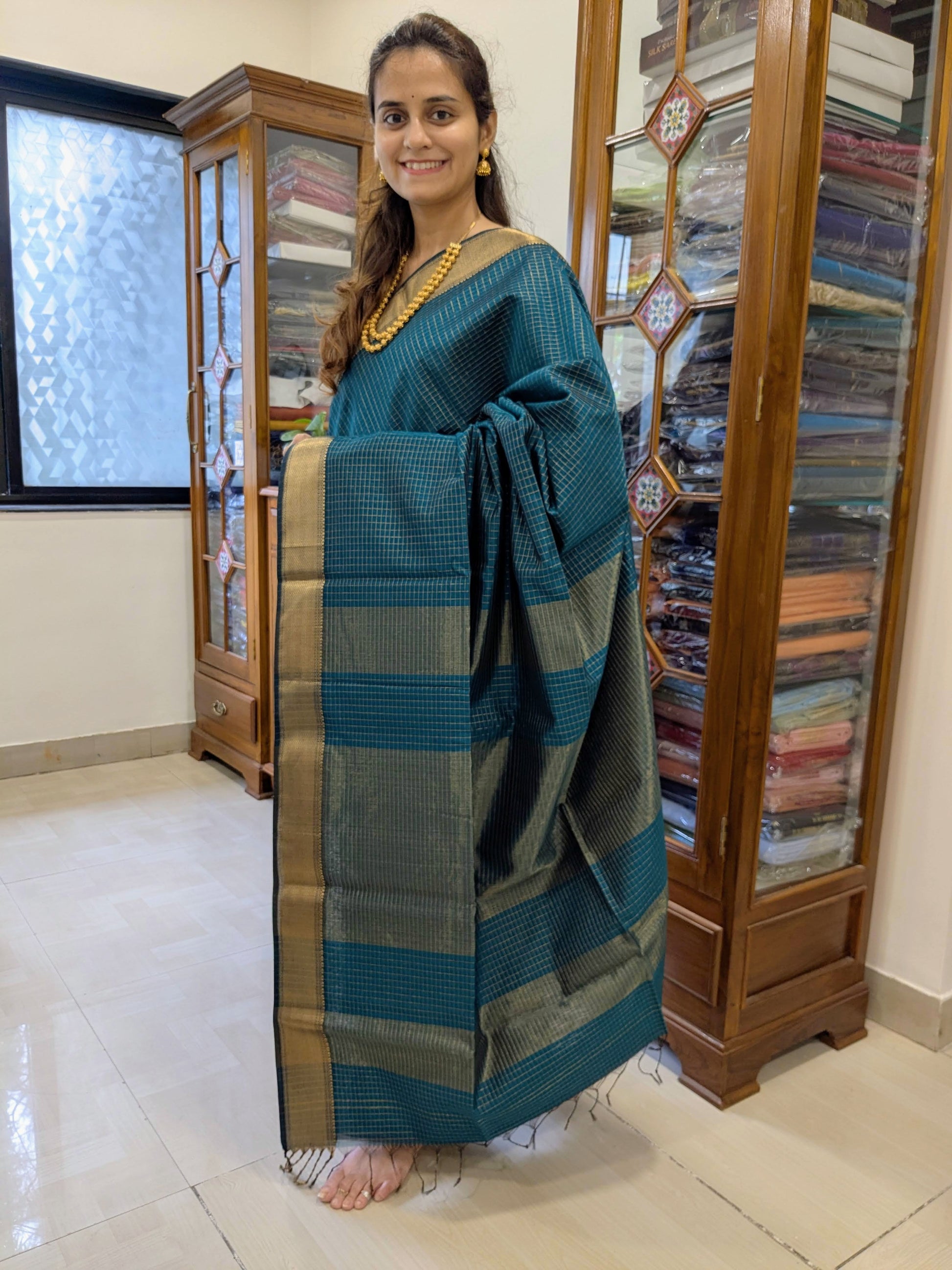 Full front view of elegant peacock blue handloom Maheshwari saree featuring golden check design and festive charm.