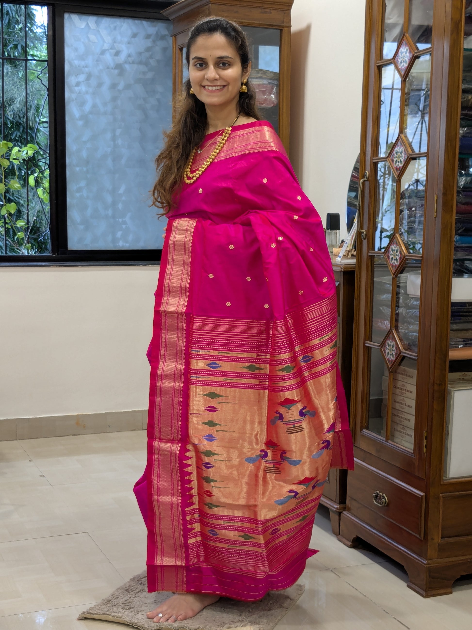 Full front view showcasing vibrant hot pink body with traditional handwoven peacock designs on the pallu.