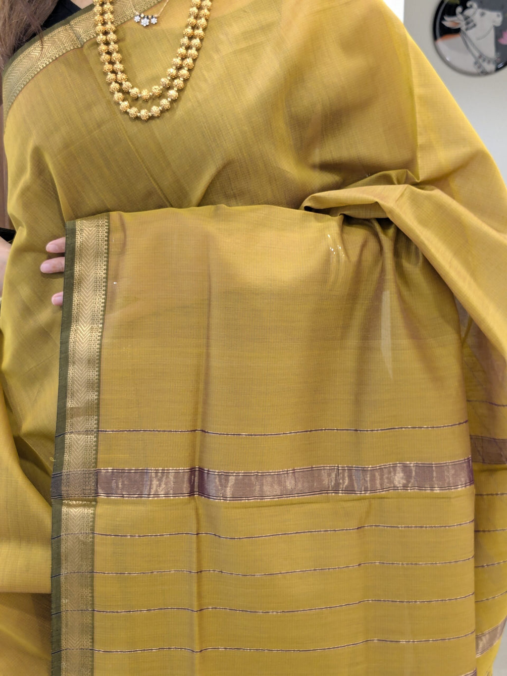Close-up of sonsali golden Maheshwari silk-cotton saree with linear patterns, small zari border