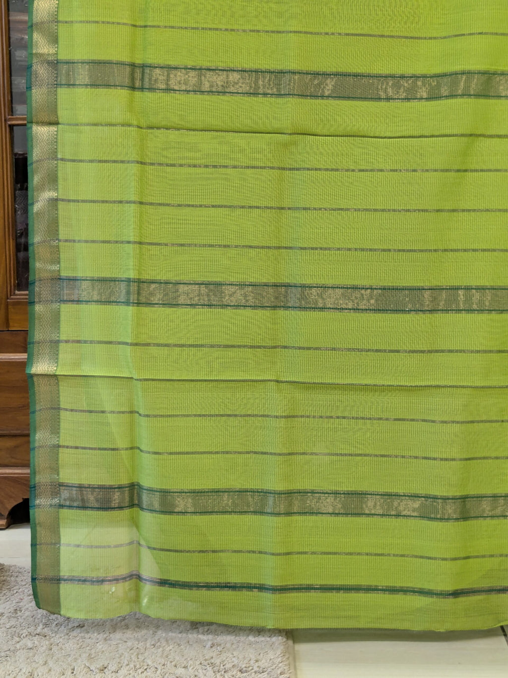 Detailed image of zari-lined pallu with shimmering golden stripes in classic Maheshwari weaving.  
