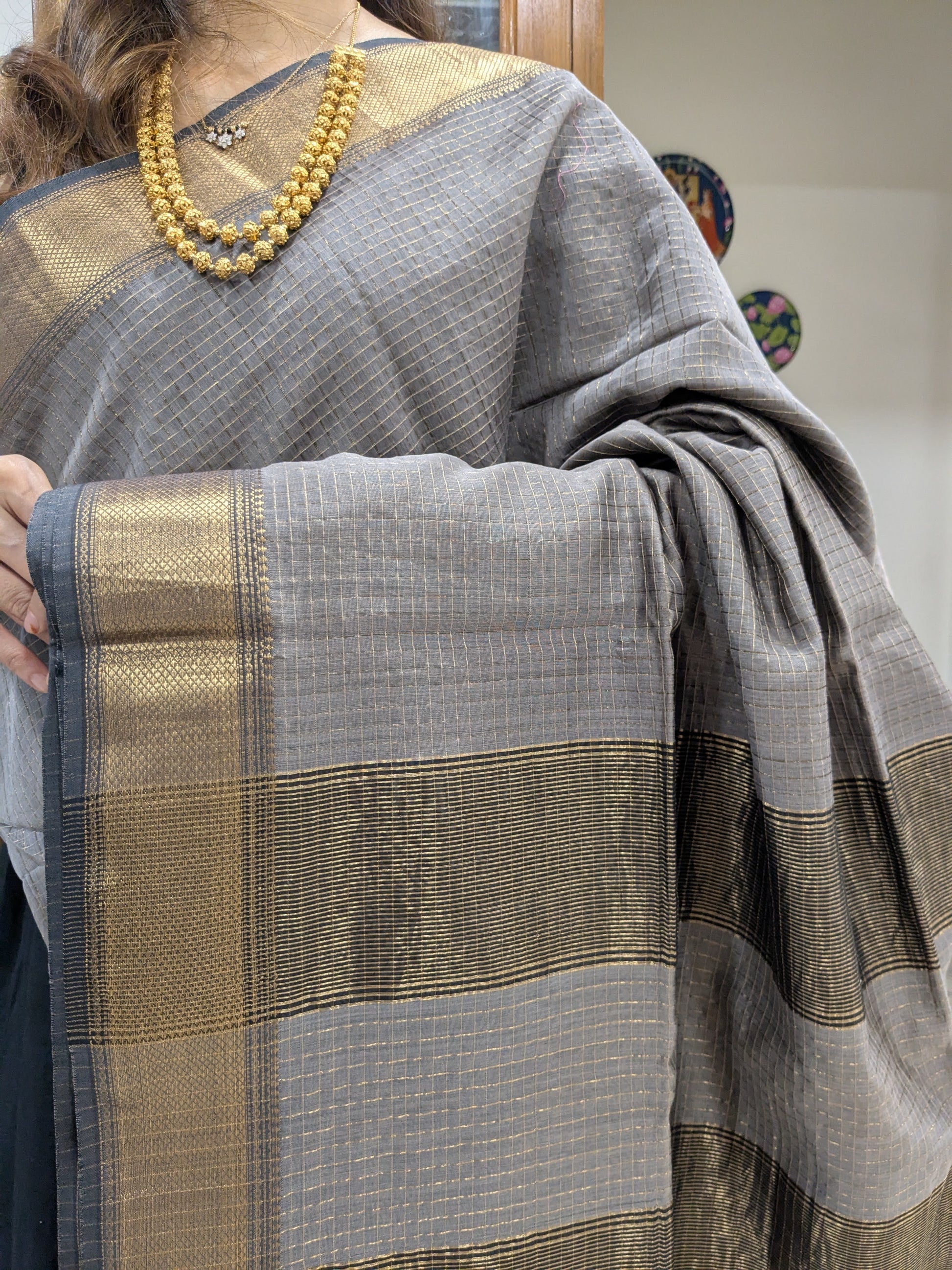 Close-up of grey Maheshwari saree featuring silk-cotton texture, zari checks, and handwoven medium border.