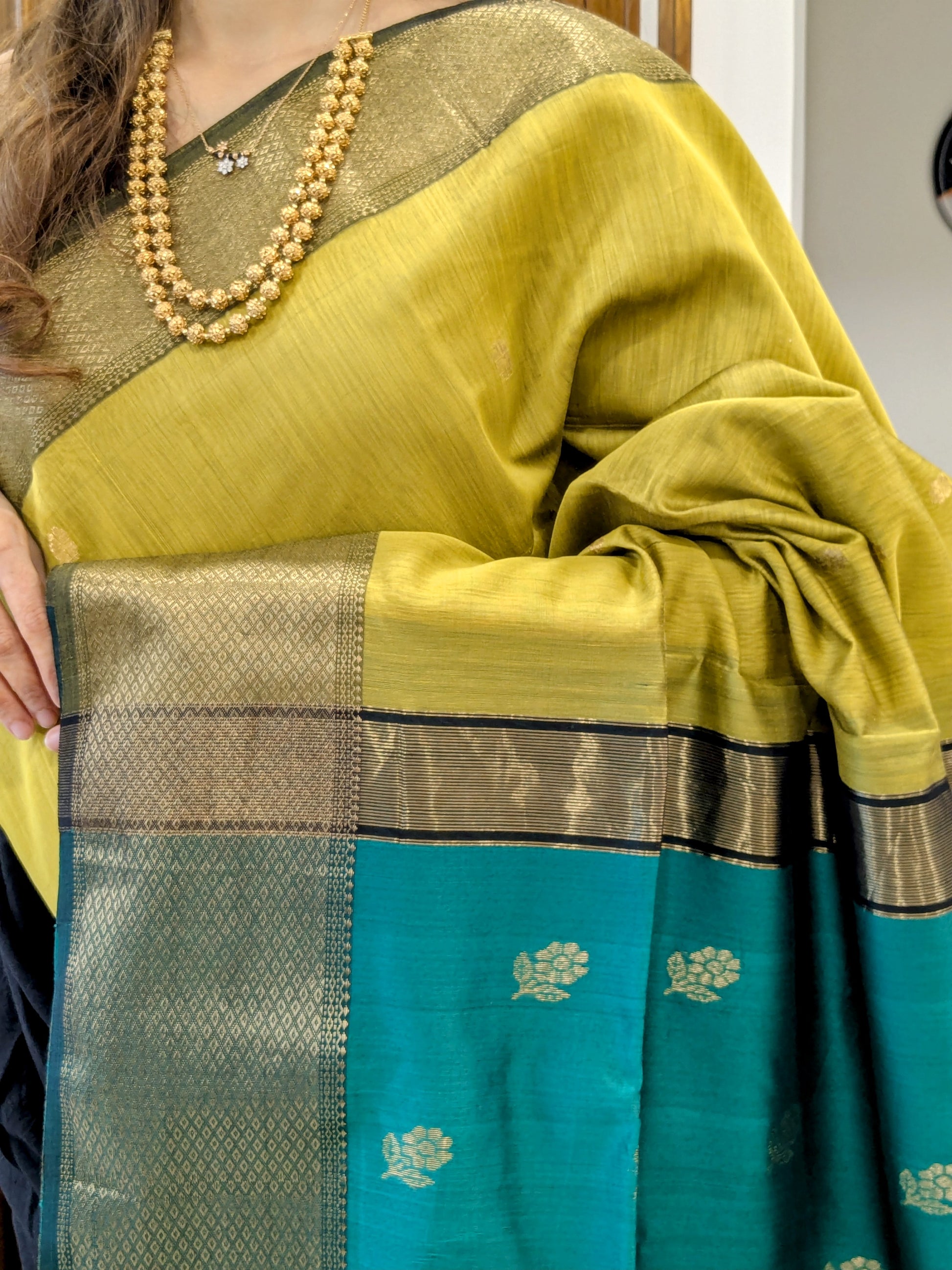 Close-up of mehendi green Maheshwari silk-cotton saree with flower butti motifs, wide & narrow border