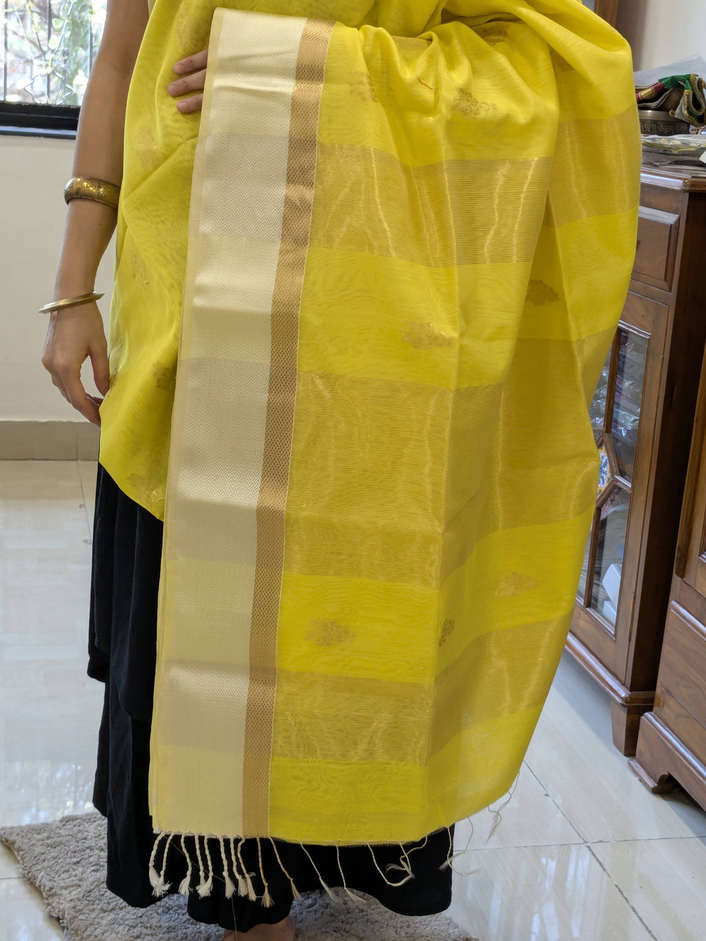 Detailed image of zari-lined pallu with shimmering gold lines and soft floral accents. 