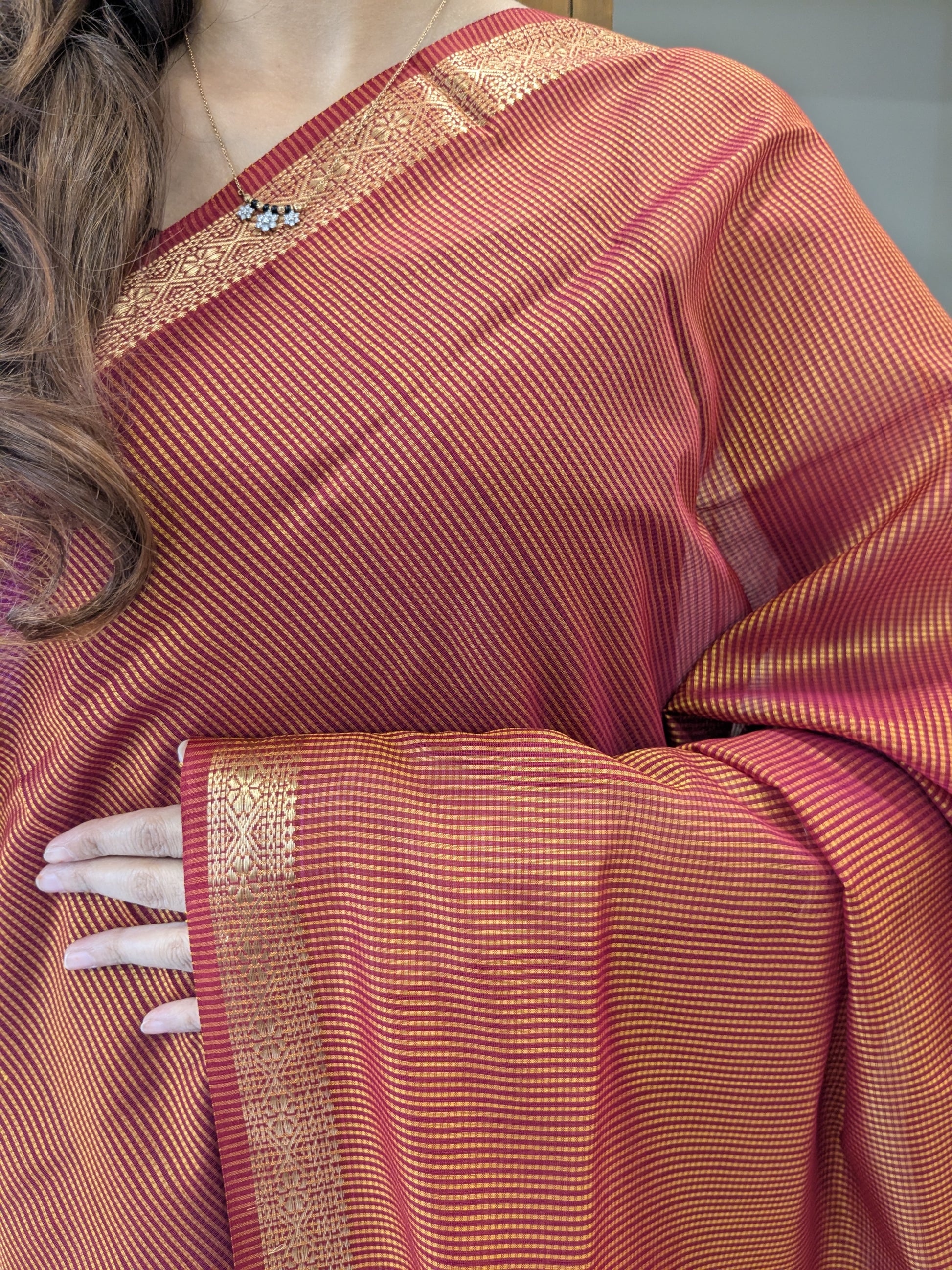 Close-up of Light Orange Maheshwari saree with small checks, vintage pallu, and delicate zari border.
