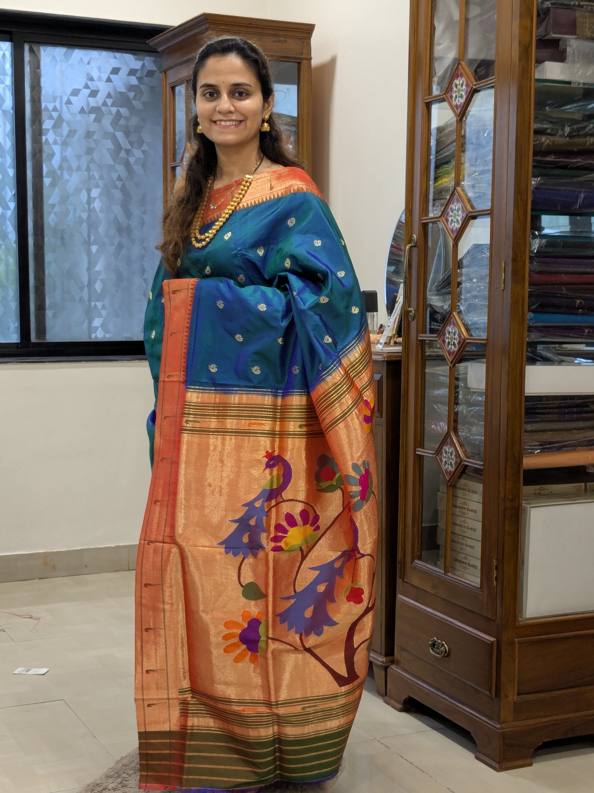 Full front view of lustrous peacock blue Paithani saree exuding festive grandeur.
