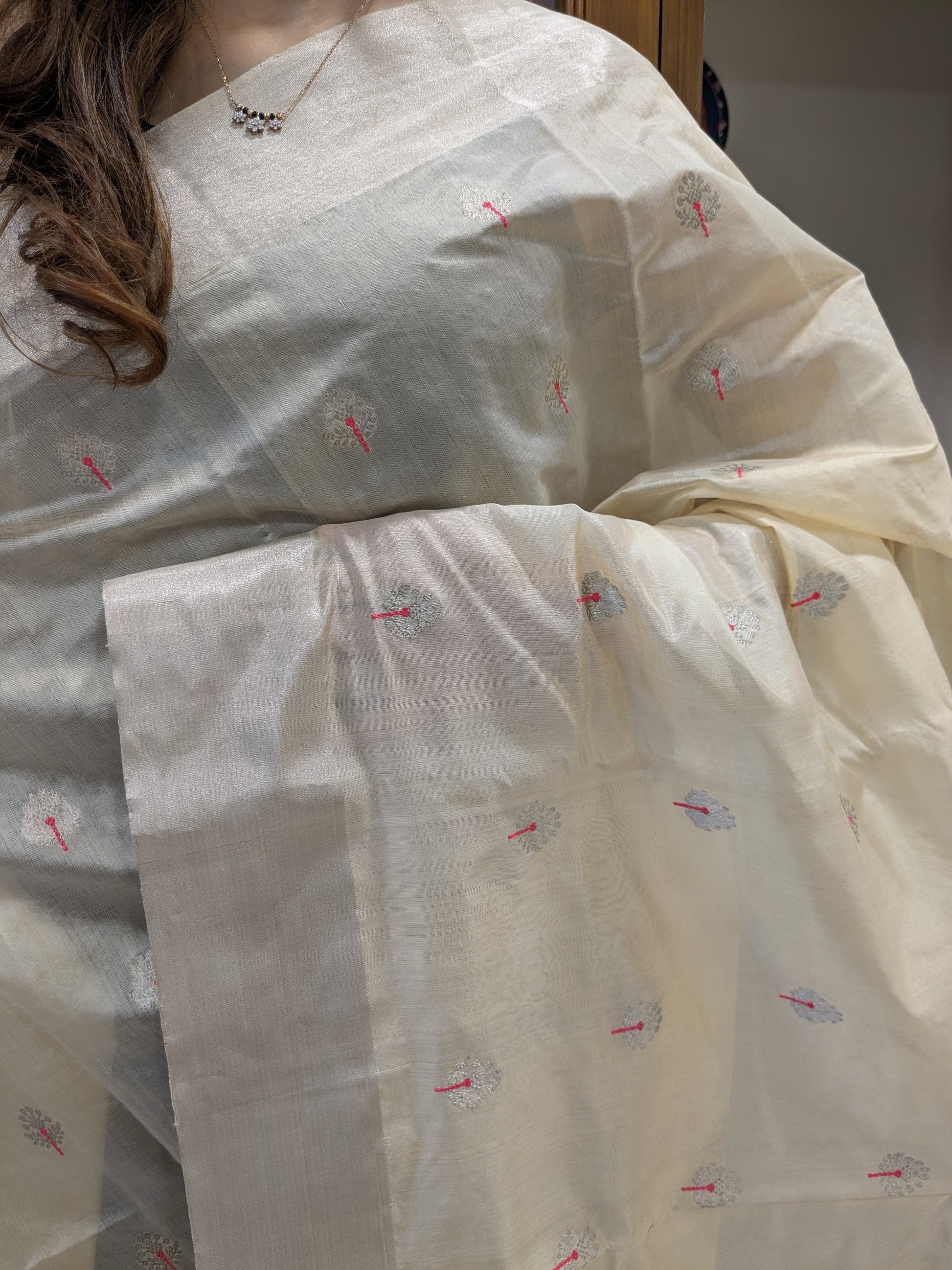 Close-up of cream Chanderi silk saree with floral motifs, handloom weave, and medium border.