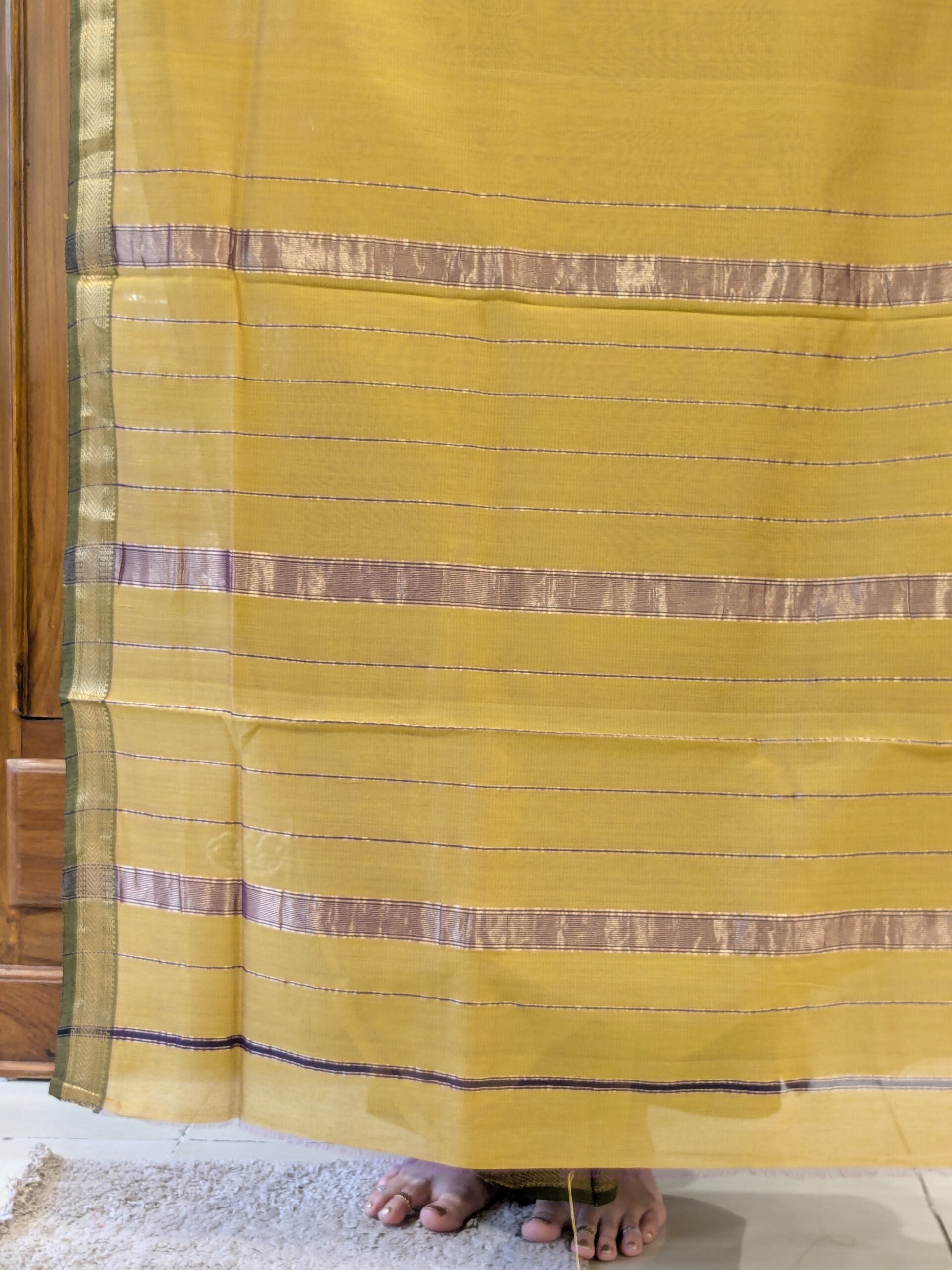 Detailed image of zari-lined pallu with fine golden stripes and refined handloom finish. 