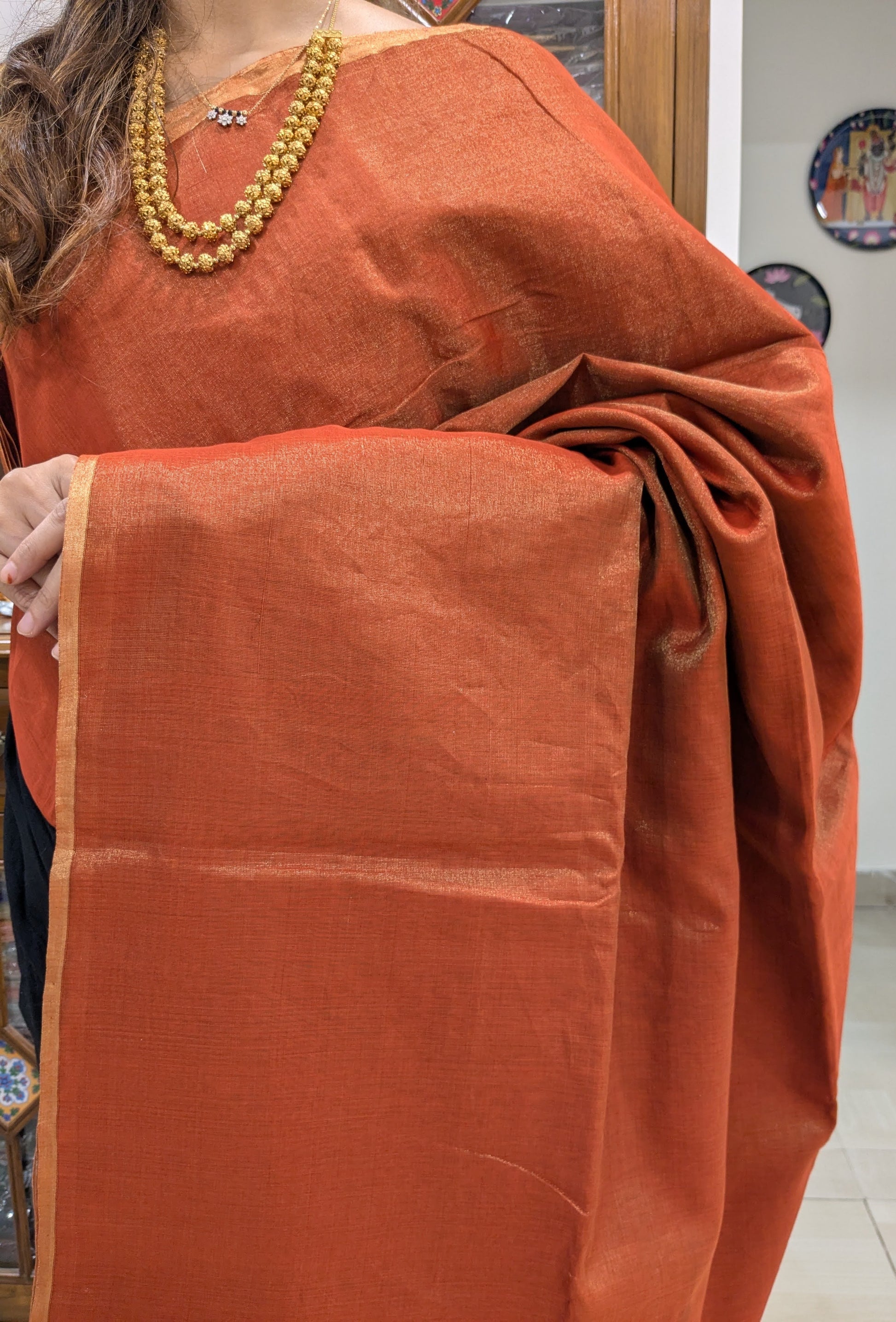 Close-up of rust orange Maheshwari saree in tissue-cotton with plain weave and handloom finish.