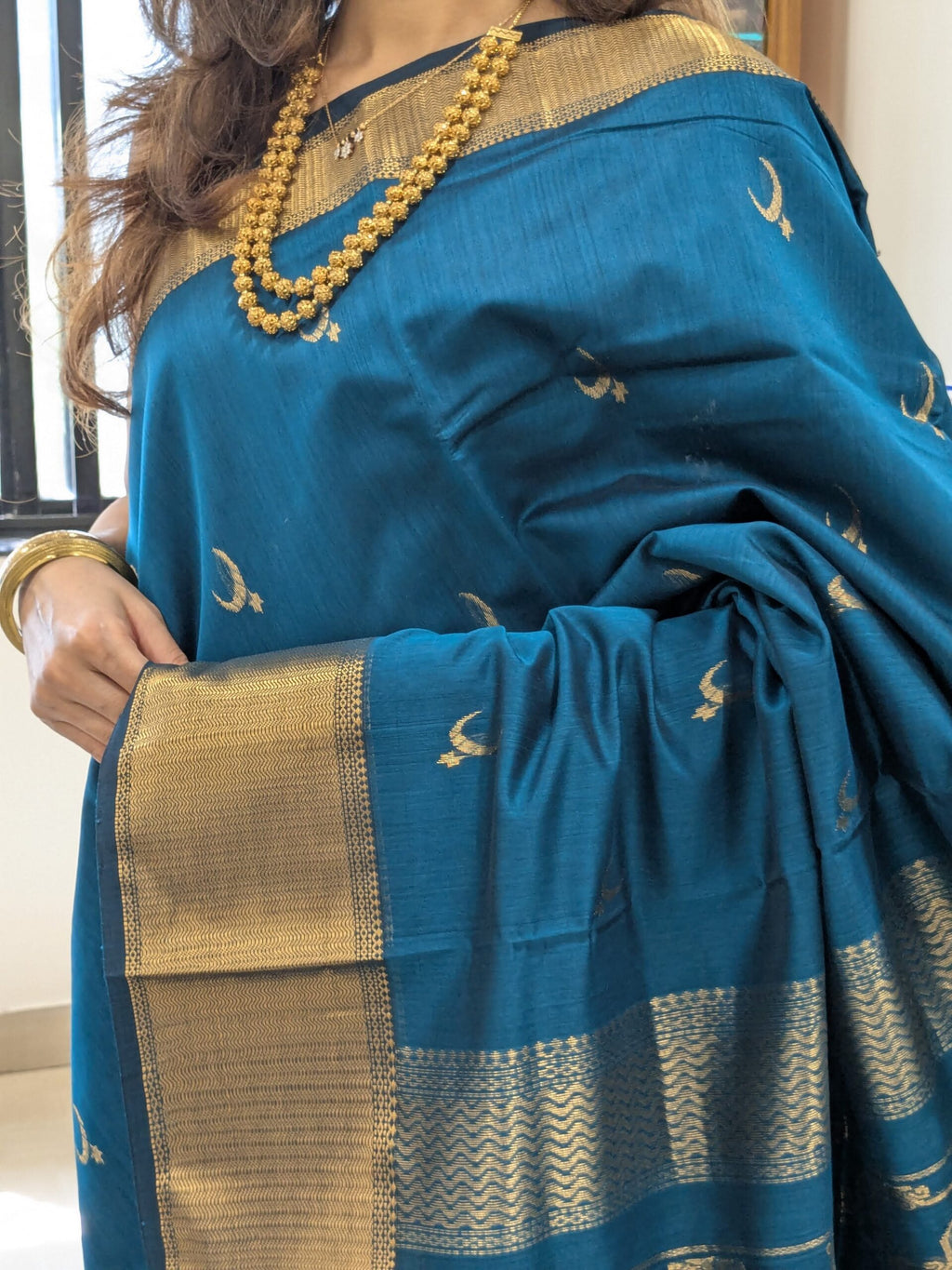 Close-up of peacock green Maheshwari saree with moon and flower motifs, wide-narrow border