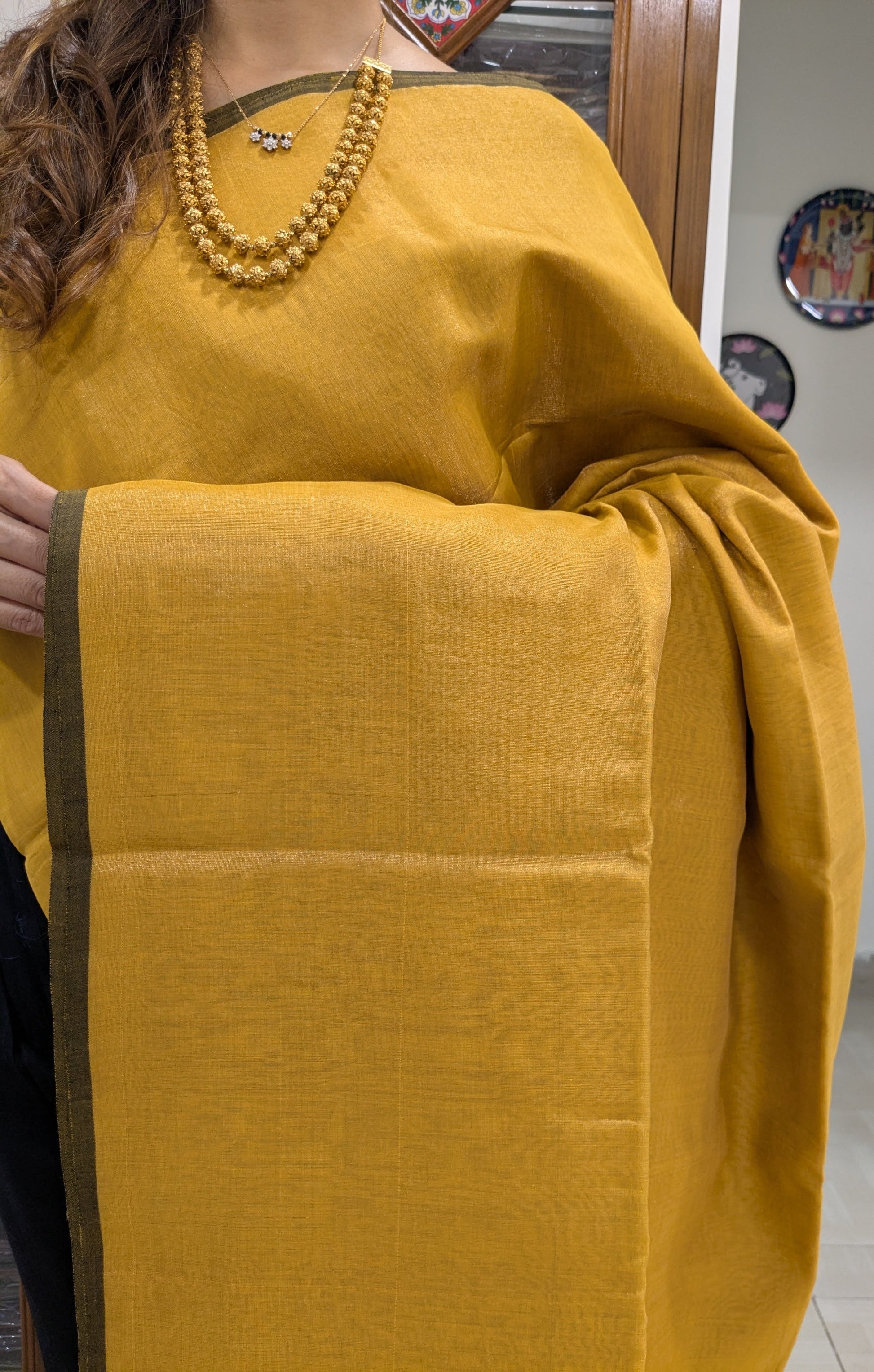 Close-up of yellow Maheshwari saree in tissue-cotton with plain handloom weave and subtle border.
