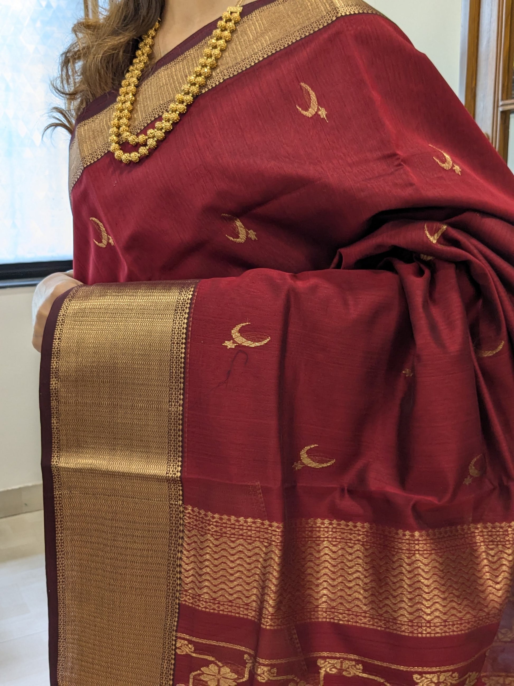 Close-up of Crimson Red Maheshwari saree with moon-flower motifs and bold jaali pallu detailing.