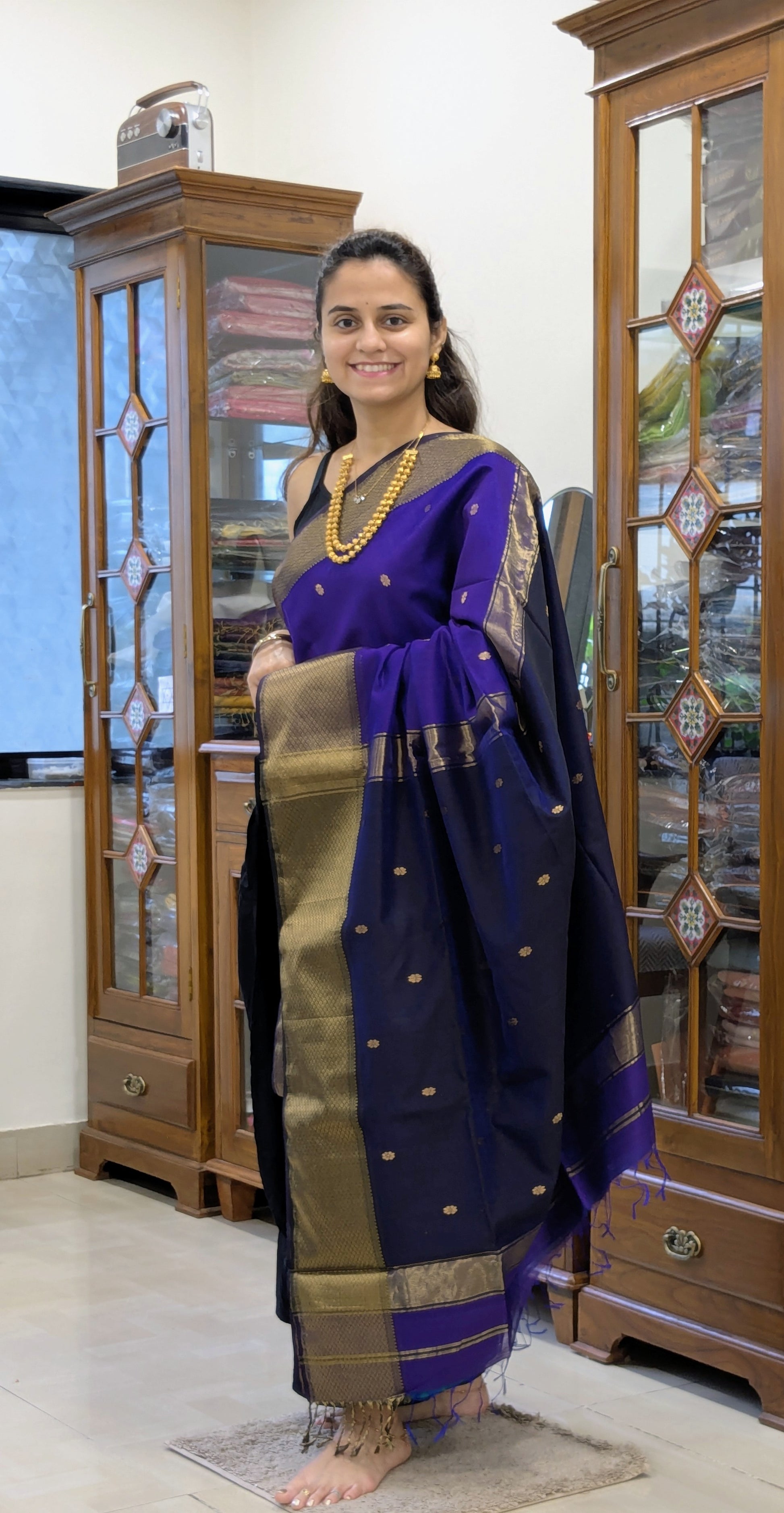 Full front view of festive purple Maheshwari saree featuring floral design and contrasting dark blue elements.  