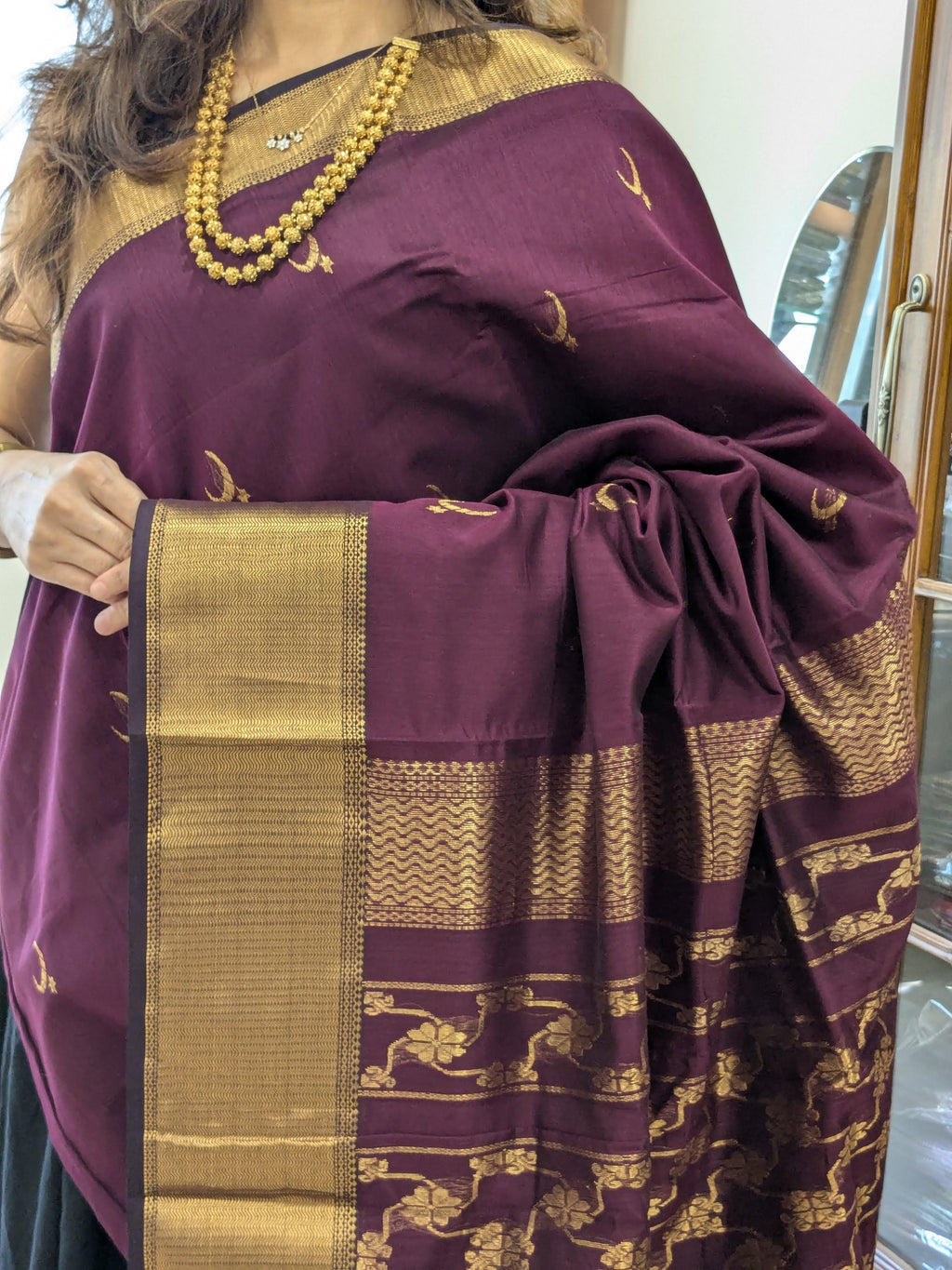 Close-up of plum purple Maheshwari saree with moon and flower motifs, wide-narrow border, and heavy jaali pallu transition.
