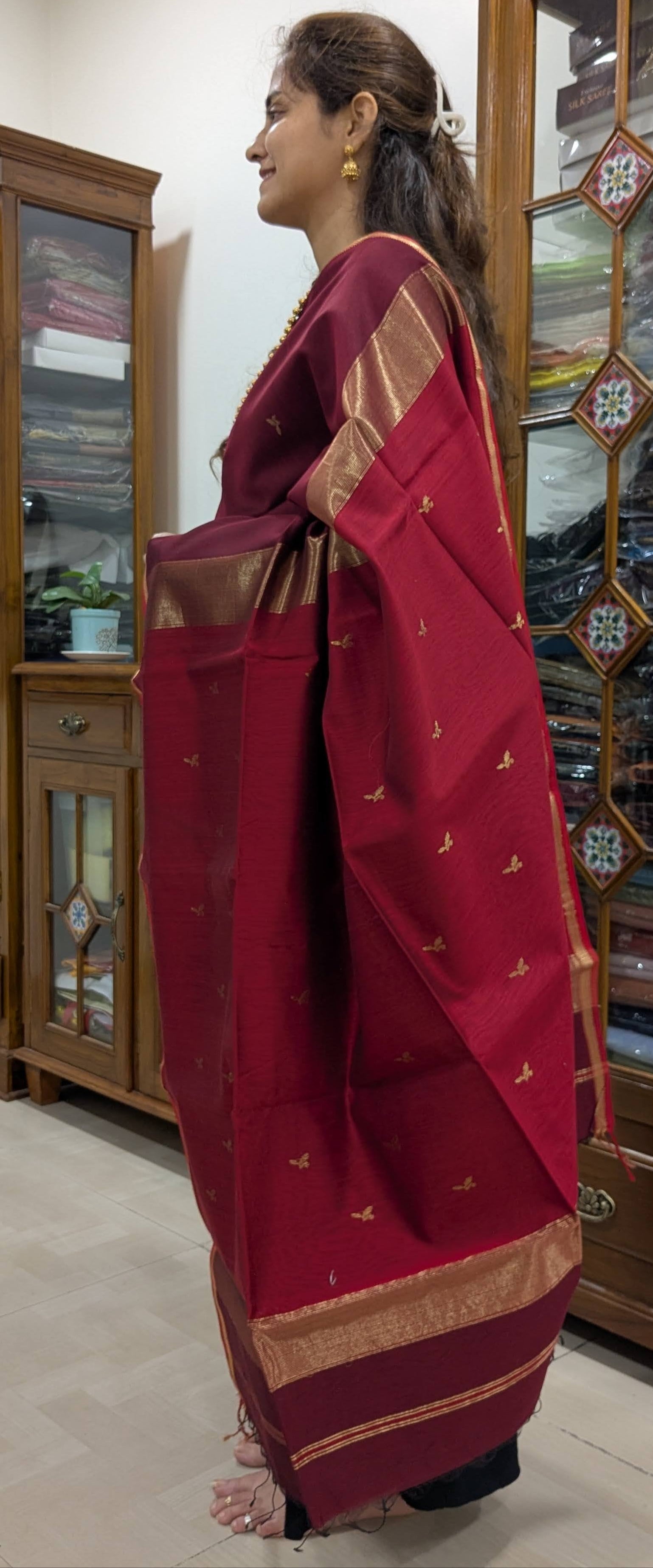 Side view showing graceful drape and texture of the handwoven maroon saree.