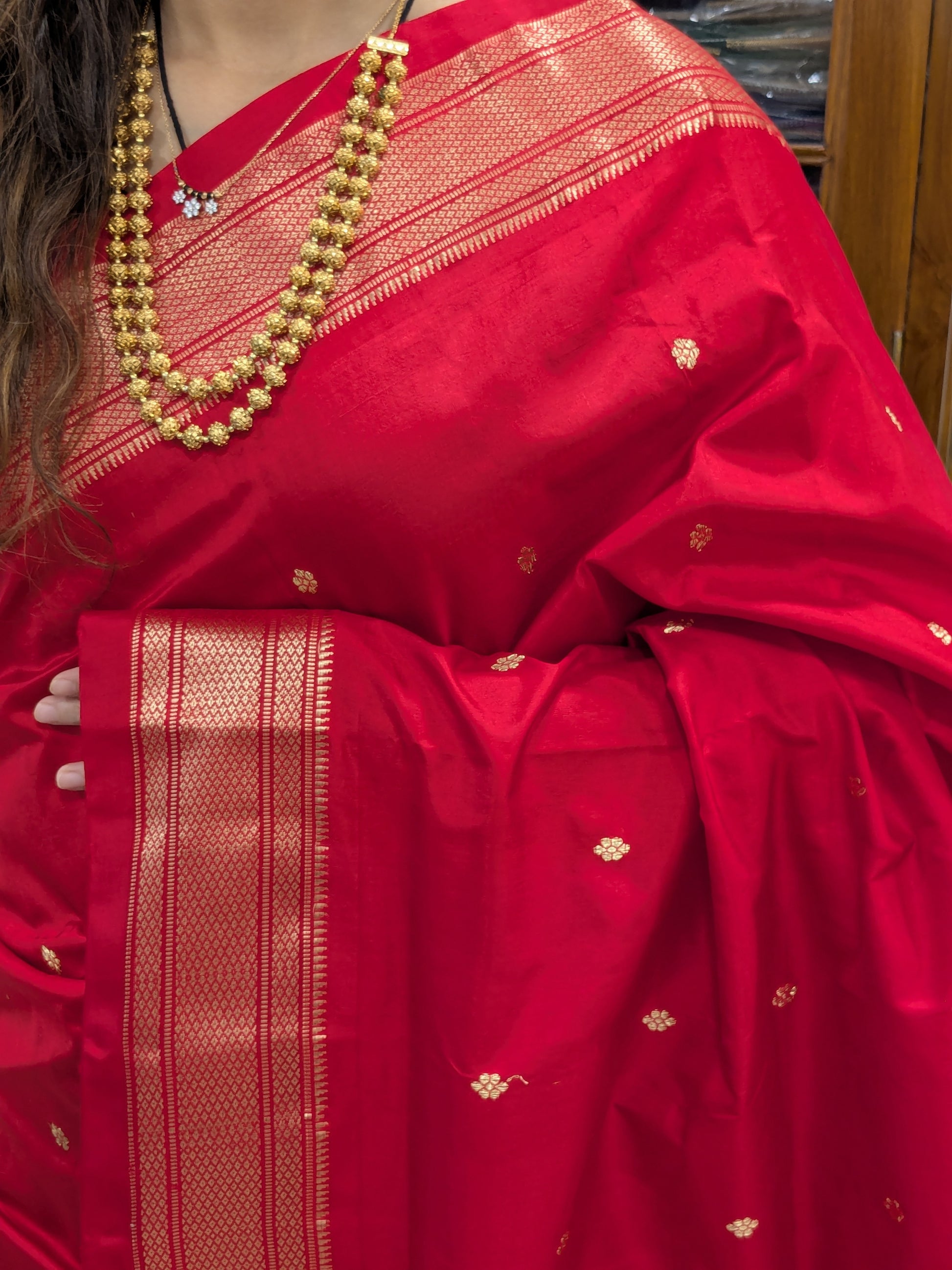 Close-up of rich tomato red Paithani saree in 100% pure silk with intricate handloom weave.