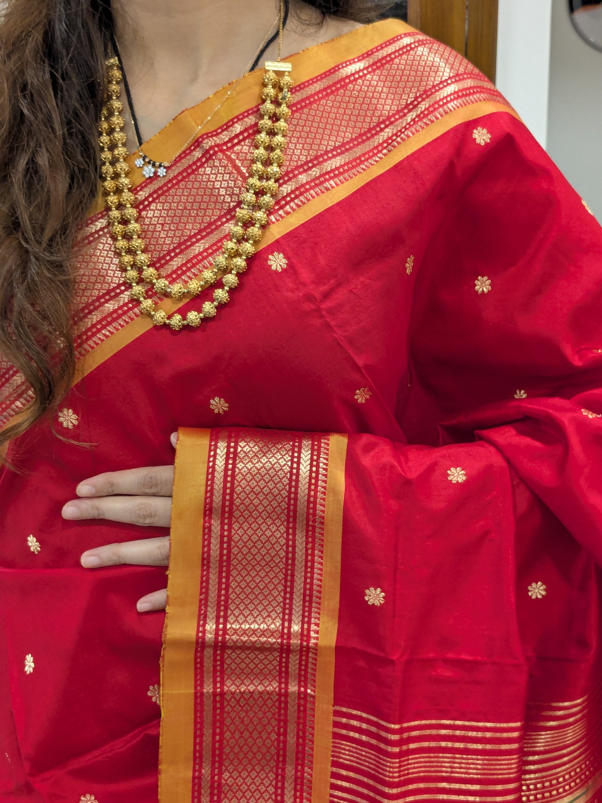 Close-up of fresh red pure silk Paithani with delicate flower motifs and Narali border.