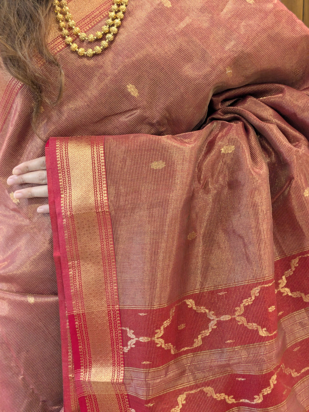 Close-up of Tomato Red silk tissue Maheshwari saree with flower butti, jaali pallu, and small handwoven border.
