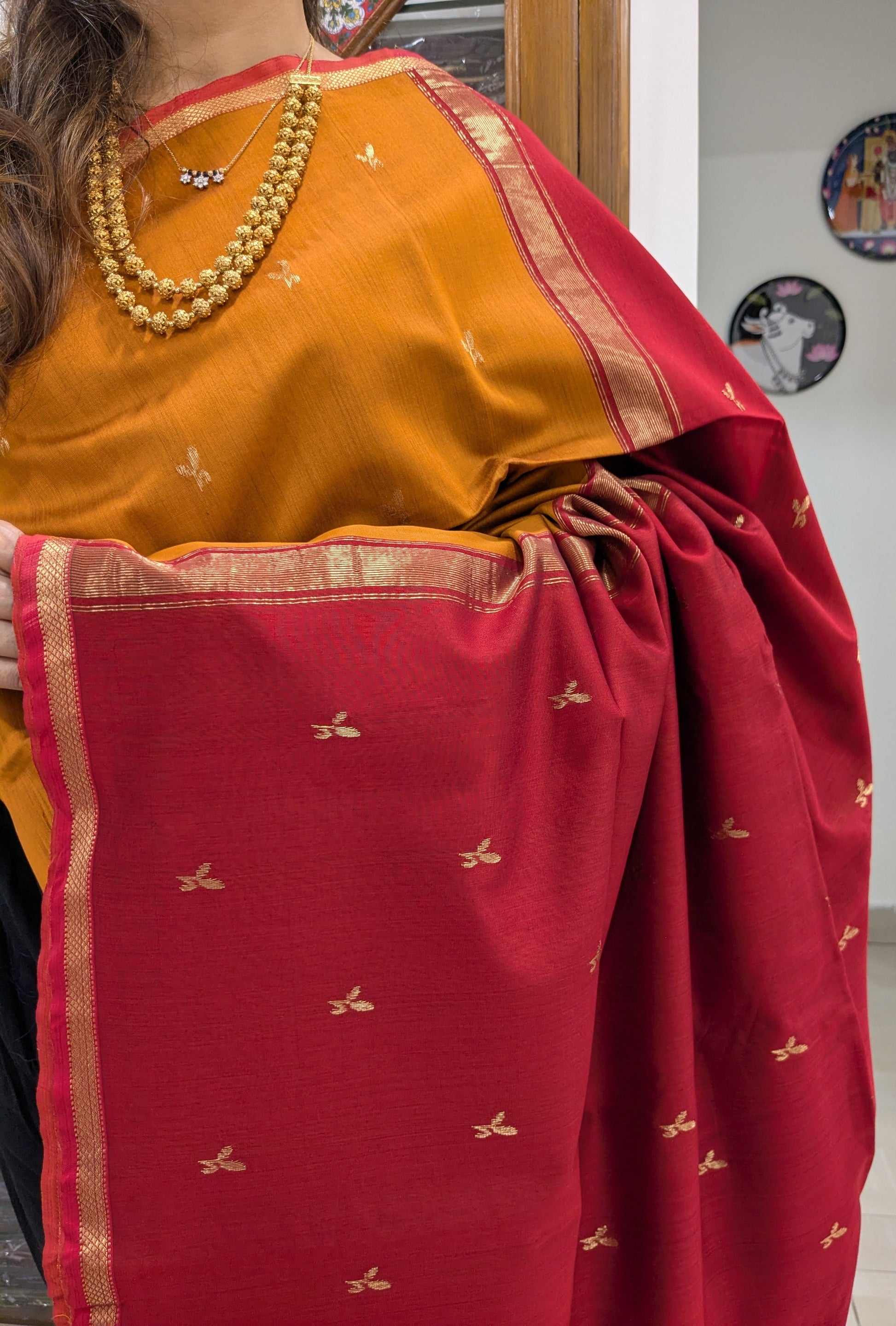 Close-up of mustard yellow Maheshwari saree with delicate leaf butti motifs and handloom-woven small border.