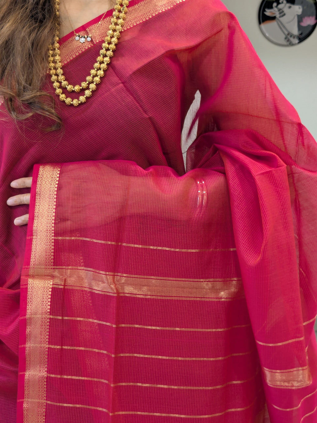 Close-up of rani pink Maheshwari silk-cotton saree with striped pattern, small zari border