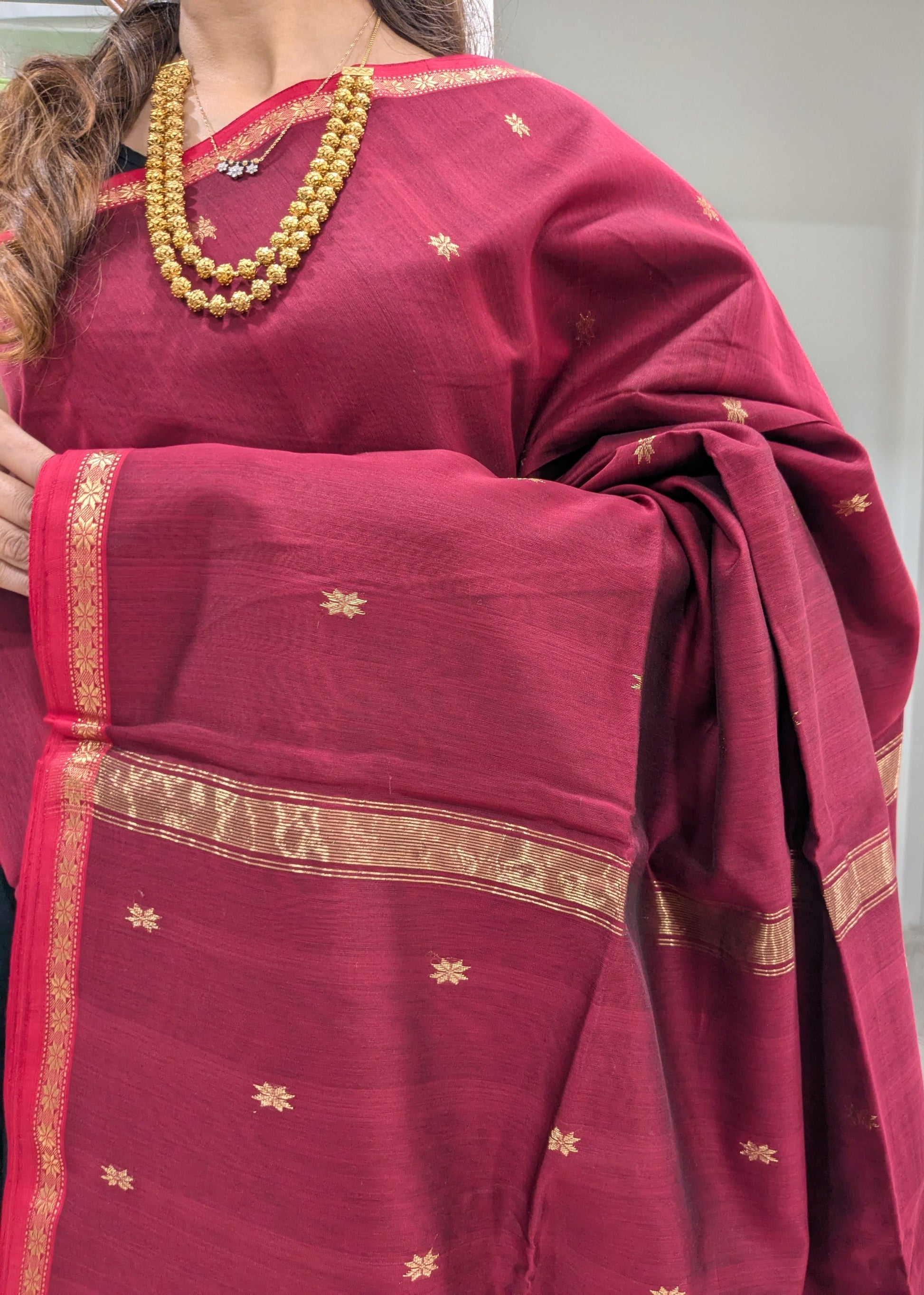 Close-up of Maroon Maheshwari saree with star butti motifs, handloom weave, and subtle small border.