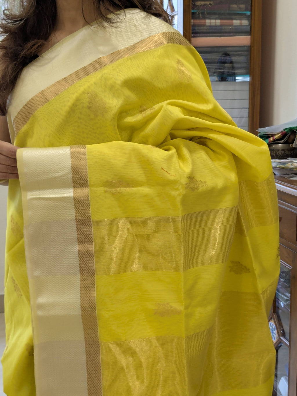 Close-up of fluorescent yellow Maheshwari silk cotton saree with floral motifs, white resham border