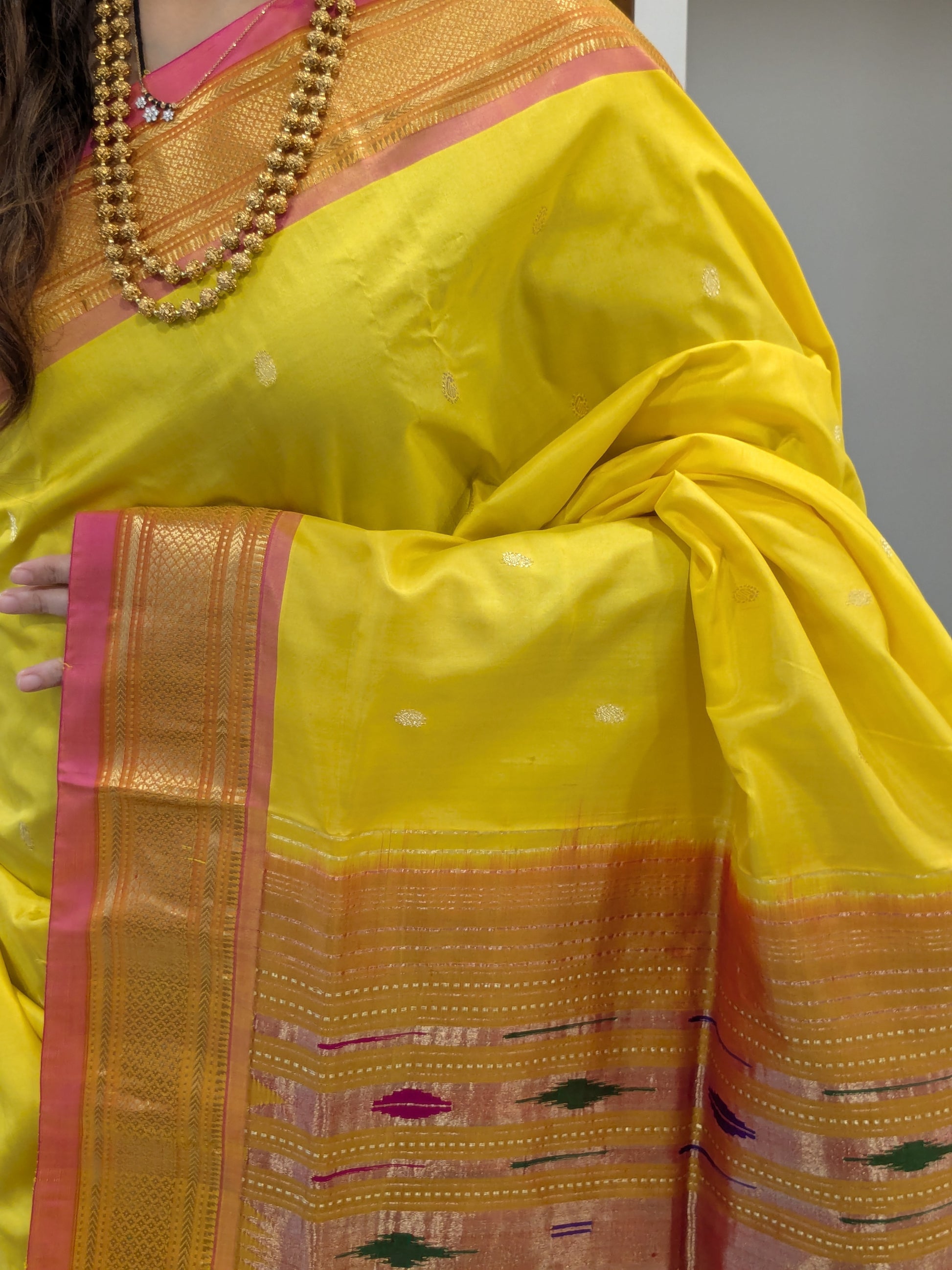 Close-up of yellow Paithani saree in pure silk with Koyri motifs, peacock pallu, and Narali border.