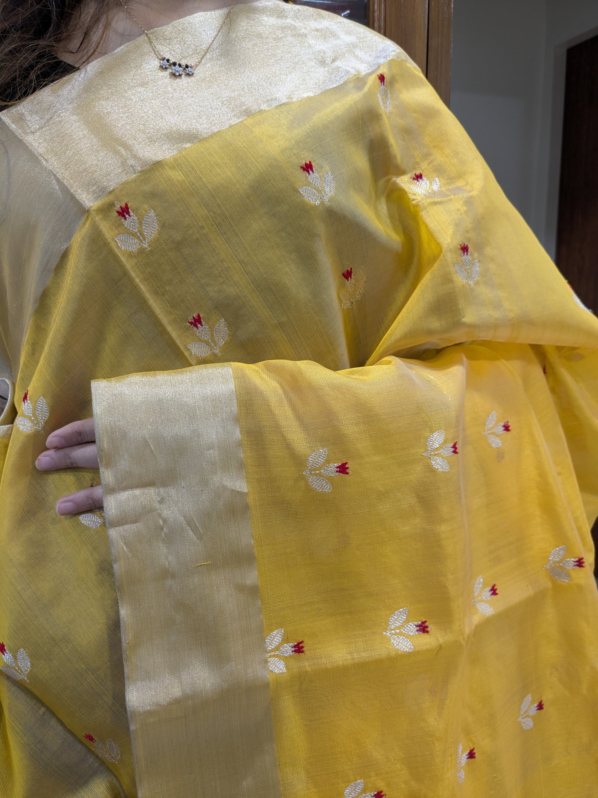 Close-up of yellow Chanderi silk saree with floral motifs, handloom weave, and medium border.