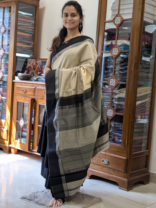 Full front view of handloom light yellow Maheshwari saree featuring subtle lines and contrasting black details.