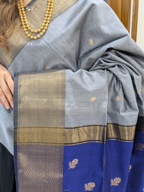 Close-up of grey and blue Maheshwari saree with flower butti, wide-narrow border