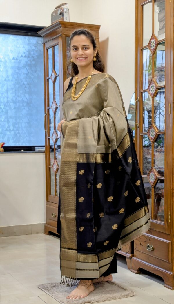 Full front view of festive grey silk-cotton Maheshwari saree featuring floral butti and intricately woven black pallu.