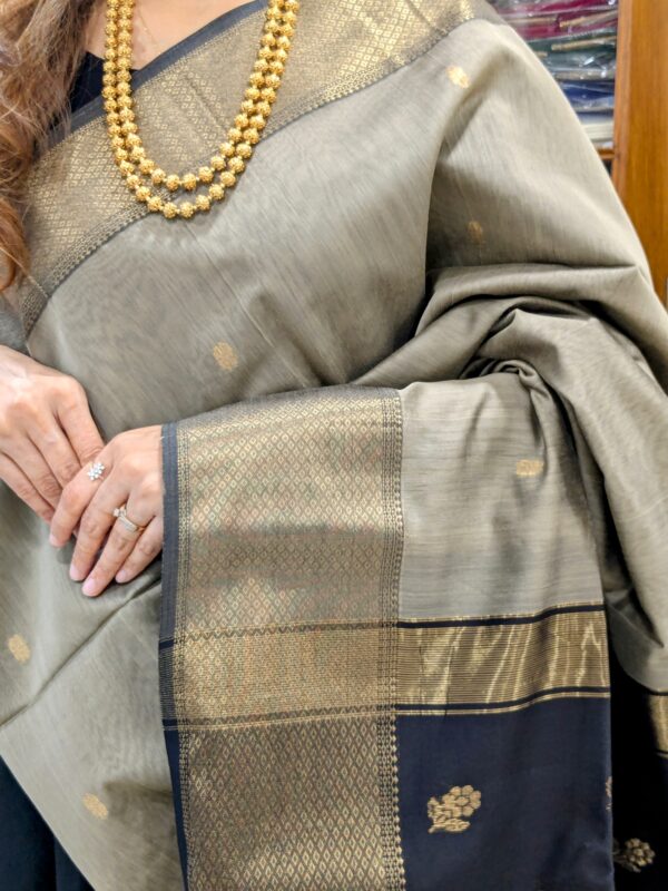 Close-up of grey and black Maheshwari saree with flower butti motifs, wide-narrow border