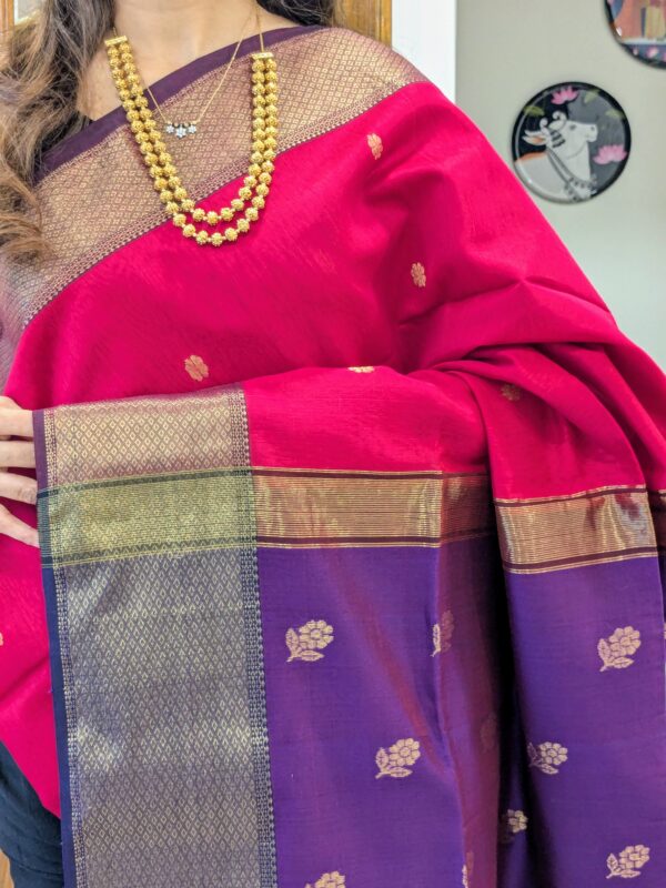 Close-up of rani pink and purple Maheshwari saree with flower butti, wide-narrow border