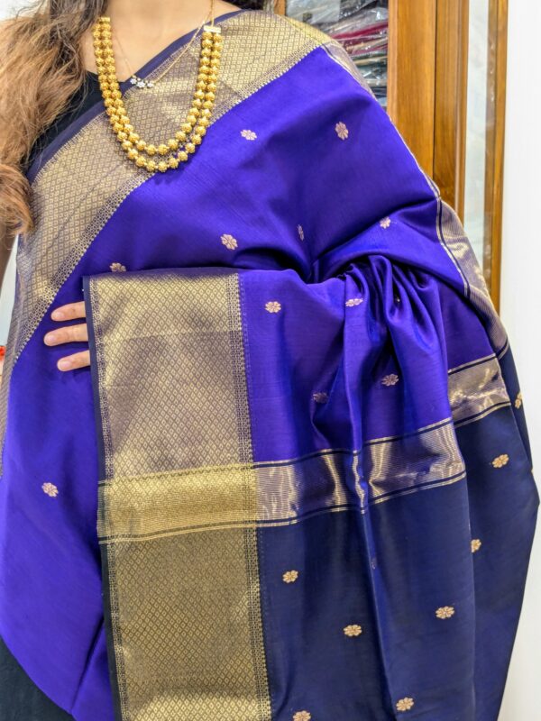 Close-up of purple and dark blue Maheshwari saree with flower butti motifs, wide-narrow border