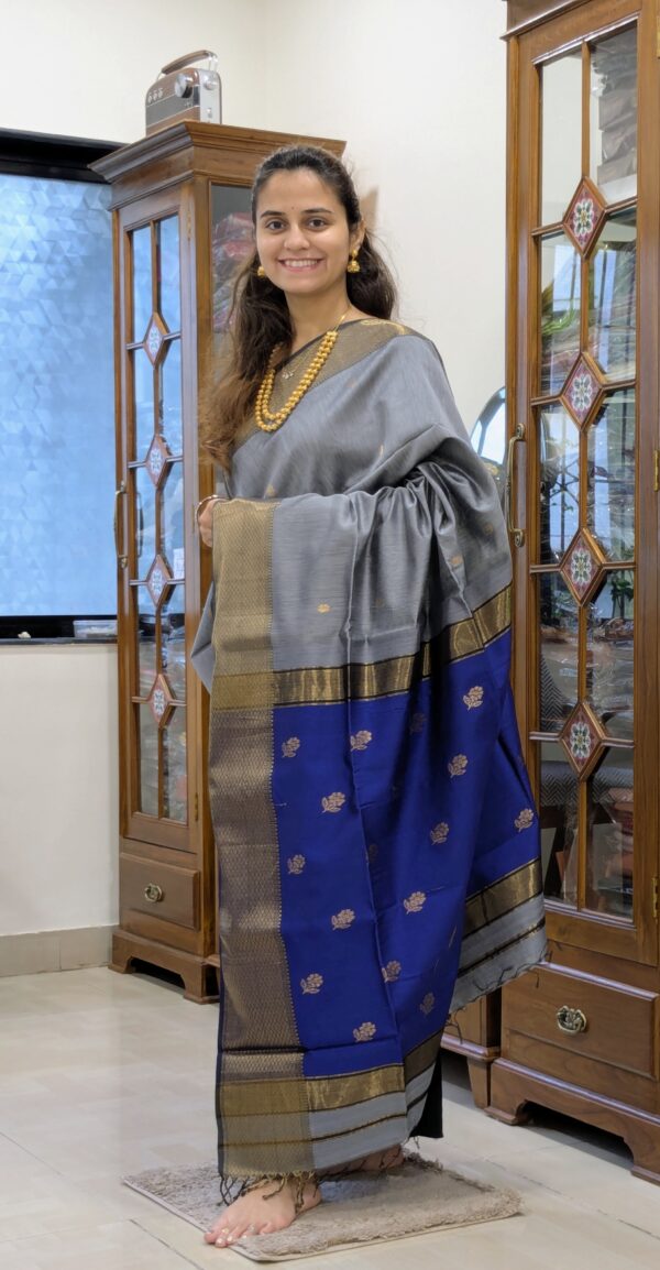 Full front view of festive grey silk-cotton Maheshwari saree featuring floral motifs and contrasting blue pallu.