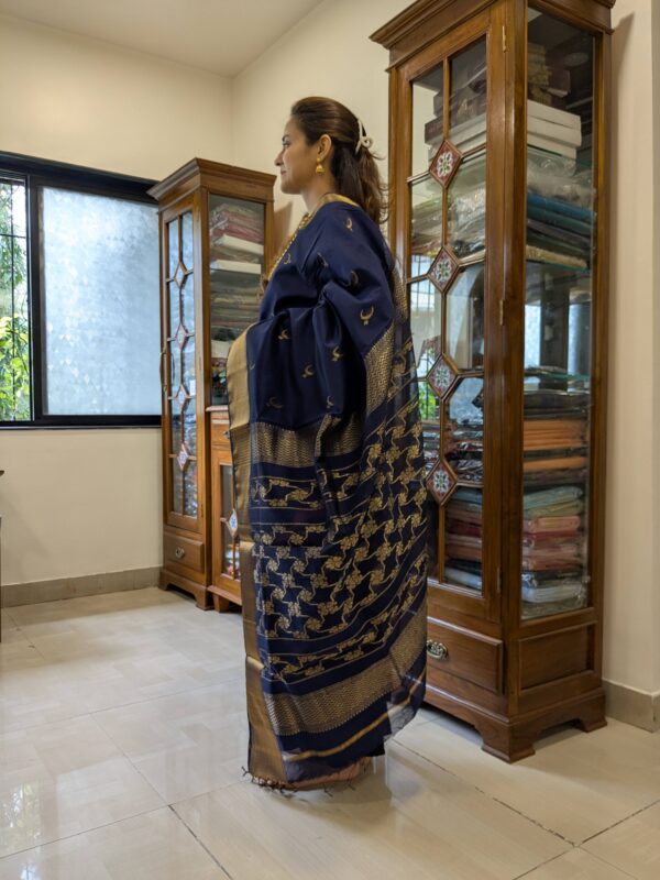 Side view of handloom deep blue saree highlighting rich drape, texture, and classic motif detailing.