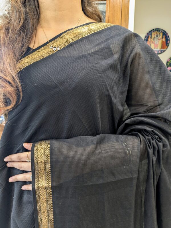 Close-up of black Maheshwari handloom saree with small checks, zari border.