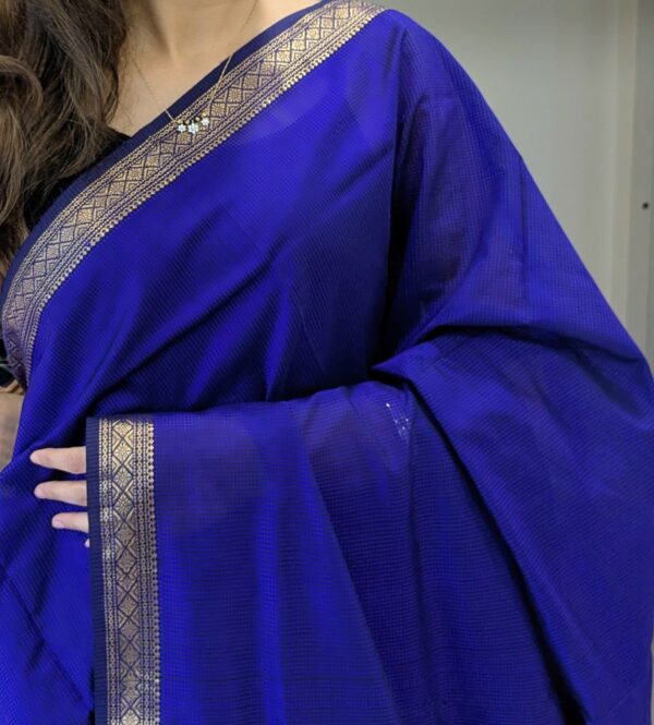 Close-up of purple Maheshwari handloom saree with small checks, delicate zari border