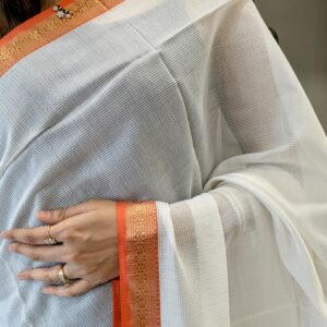 Close-up of white Maheshwari saree with small checks, handwoven texture, zari border, and vintage pallu transition.